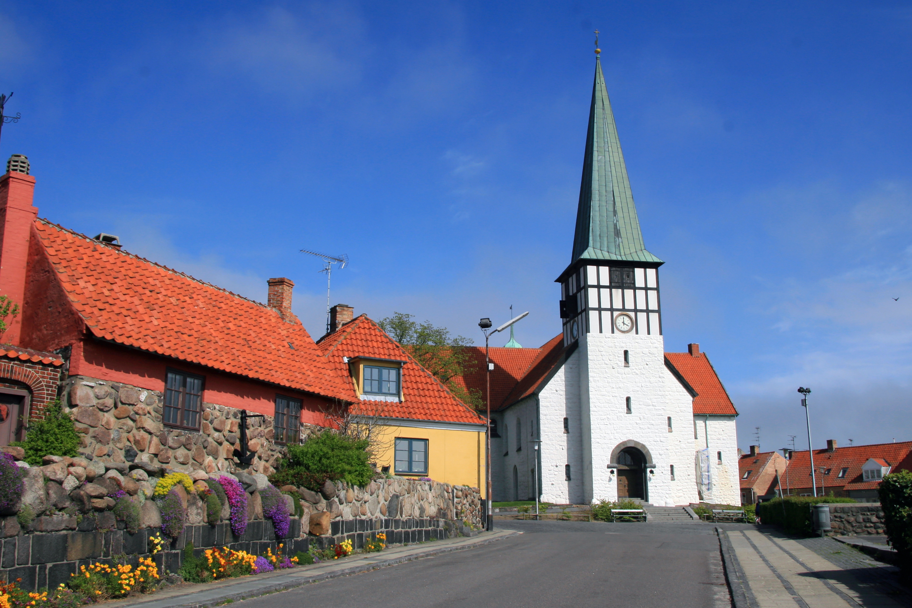 Idyllisk dansk landsbymiljø med hvid kirke og røde tegltage på Bornholm