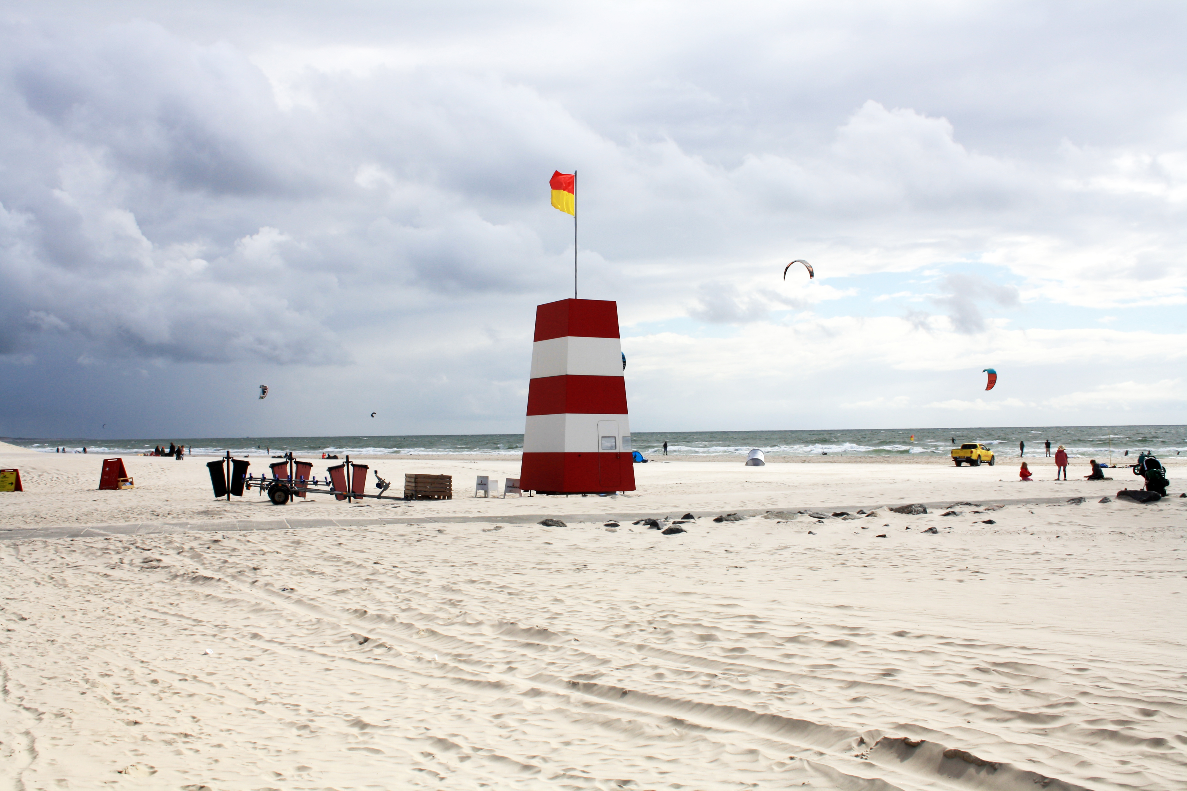 Dansk strand med ikonisk fyrtårn hvor turister nyder sommerferie ved Vestkysten