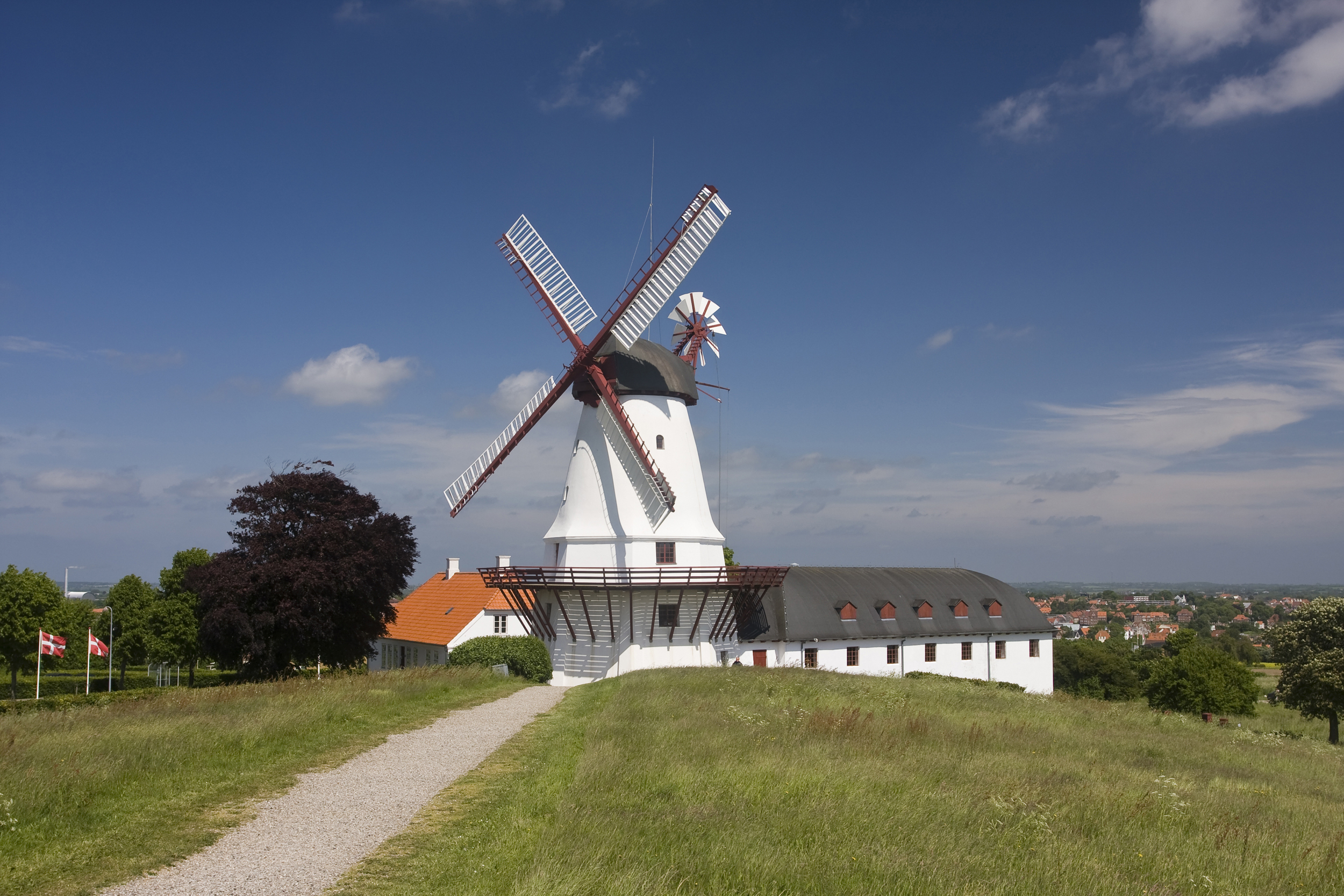 Hvid vindmølle på Dybbøl med dansk flag og blå himmel