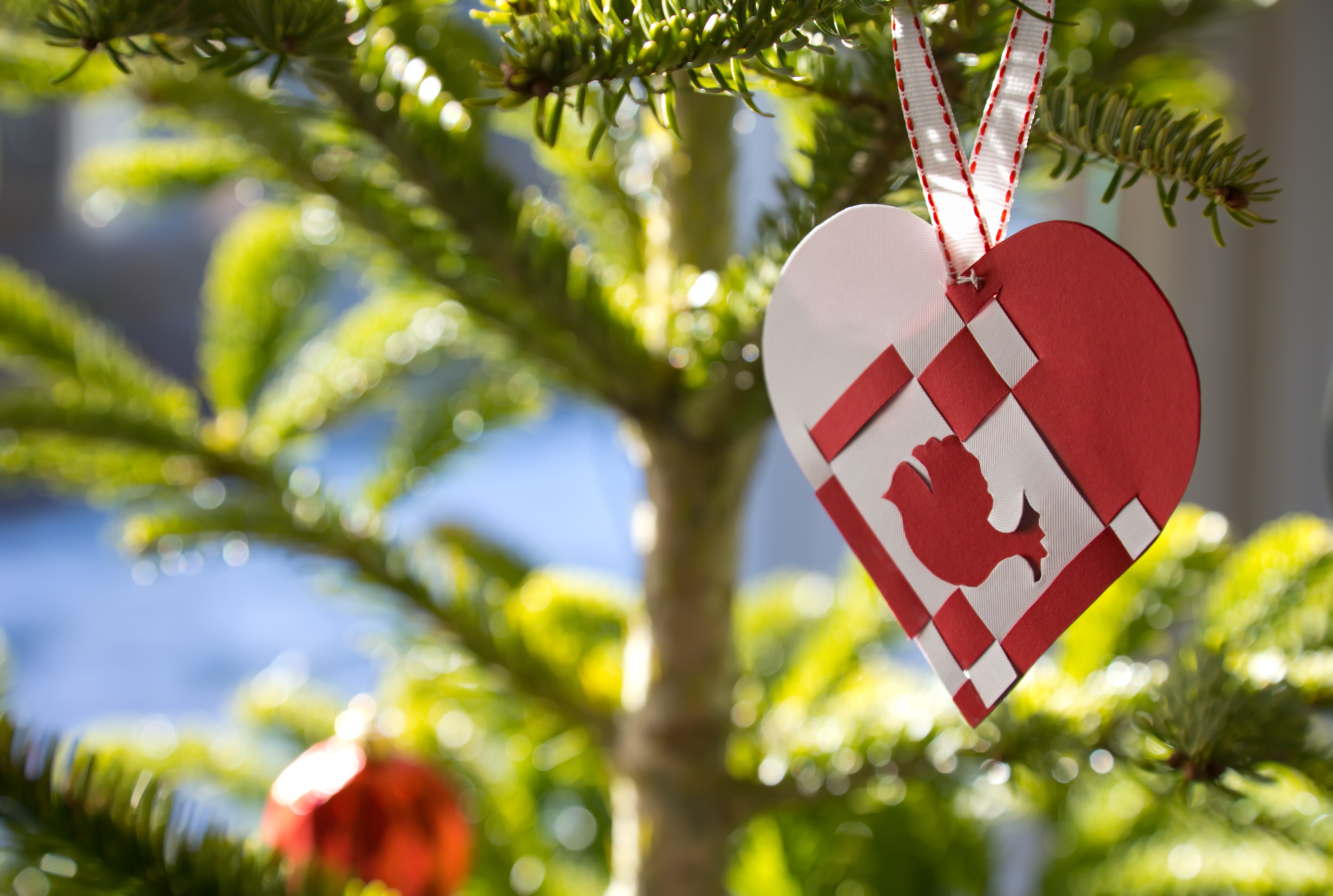 Danske juletræshjerter i røde og hvide farver med silkebånd på grønne grene