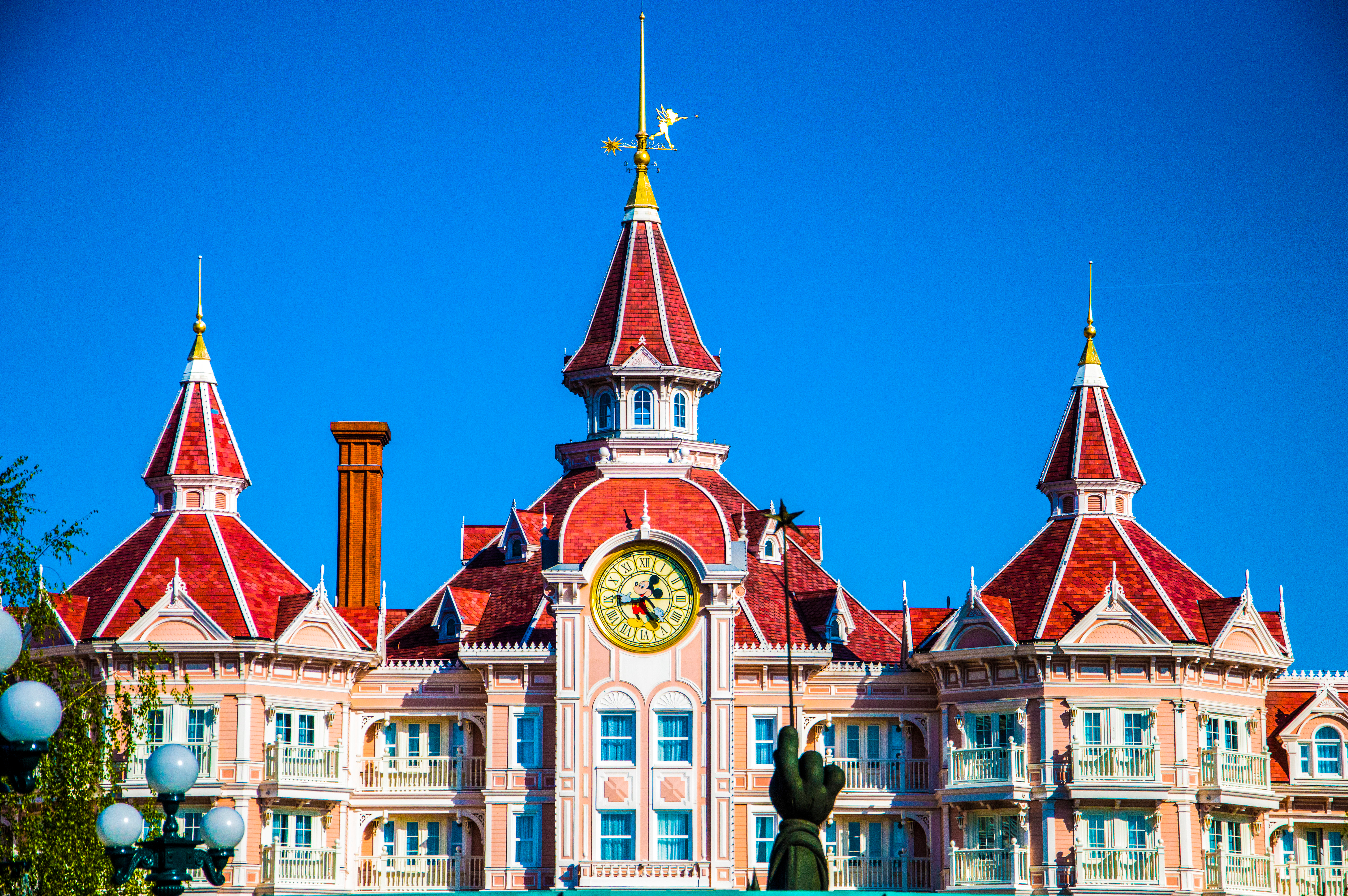 Indgangen til det eventyrlige Disneyland Paris Hotel med røde tage, Mickey Mouse-ur og gylden figur øverst på tårnet