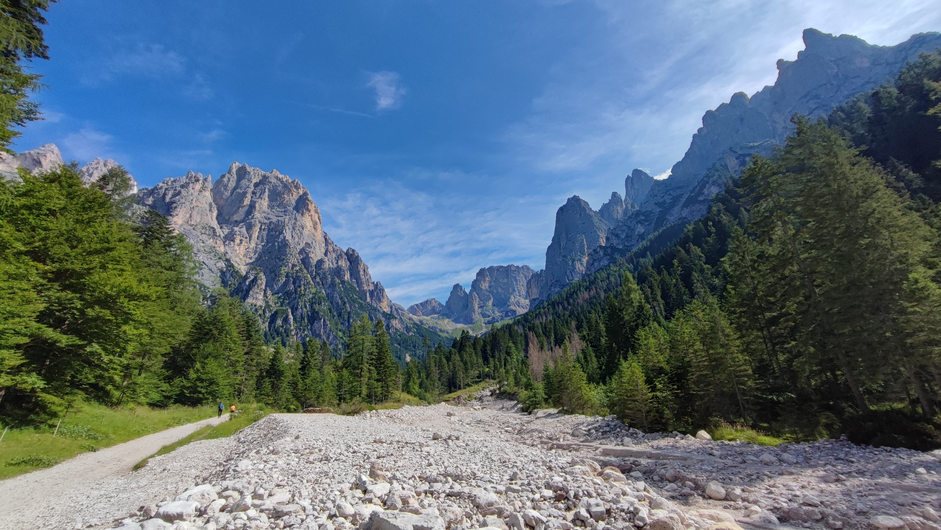 Naturskøn dal i Dolomitterne med imponerende klippetinder, grøn skov og stenet flodleje i Trentino Alto Adige, Italien