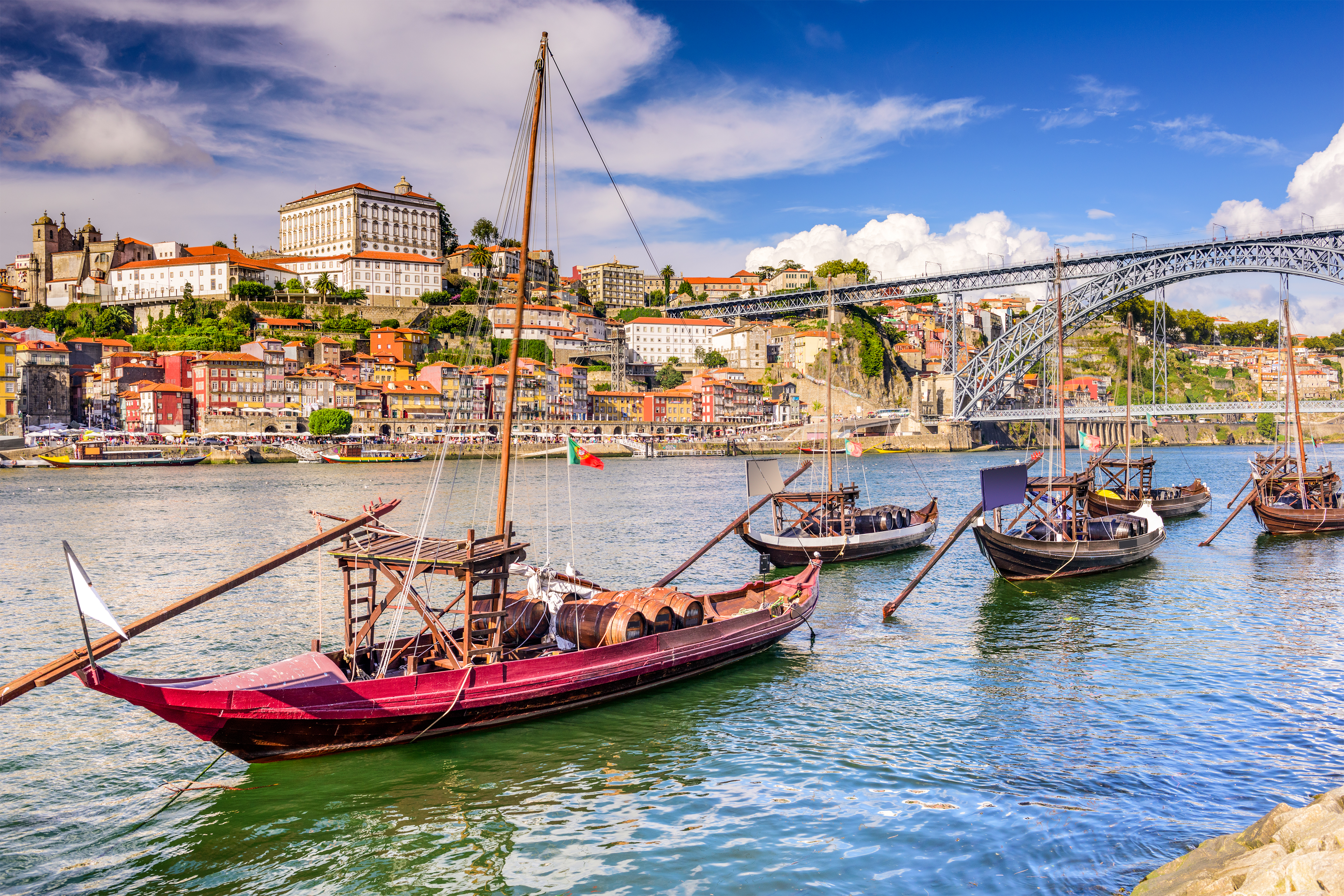 Klassiske træbåde på Douro-floden i Porto med farverige huse og den berømte Dom Luis I-bro