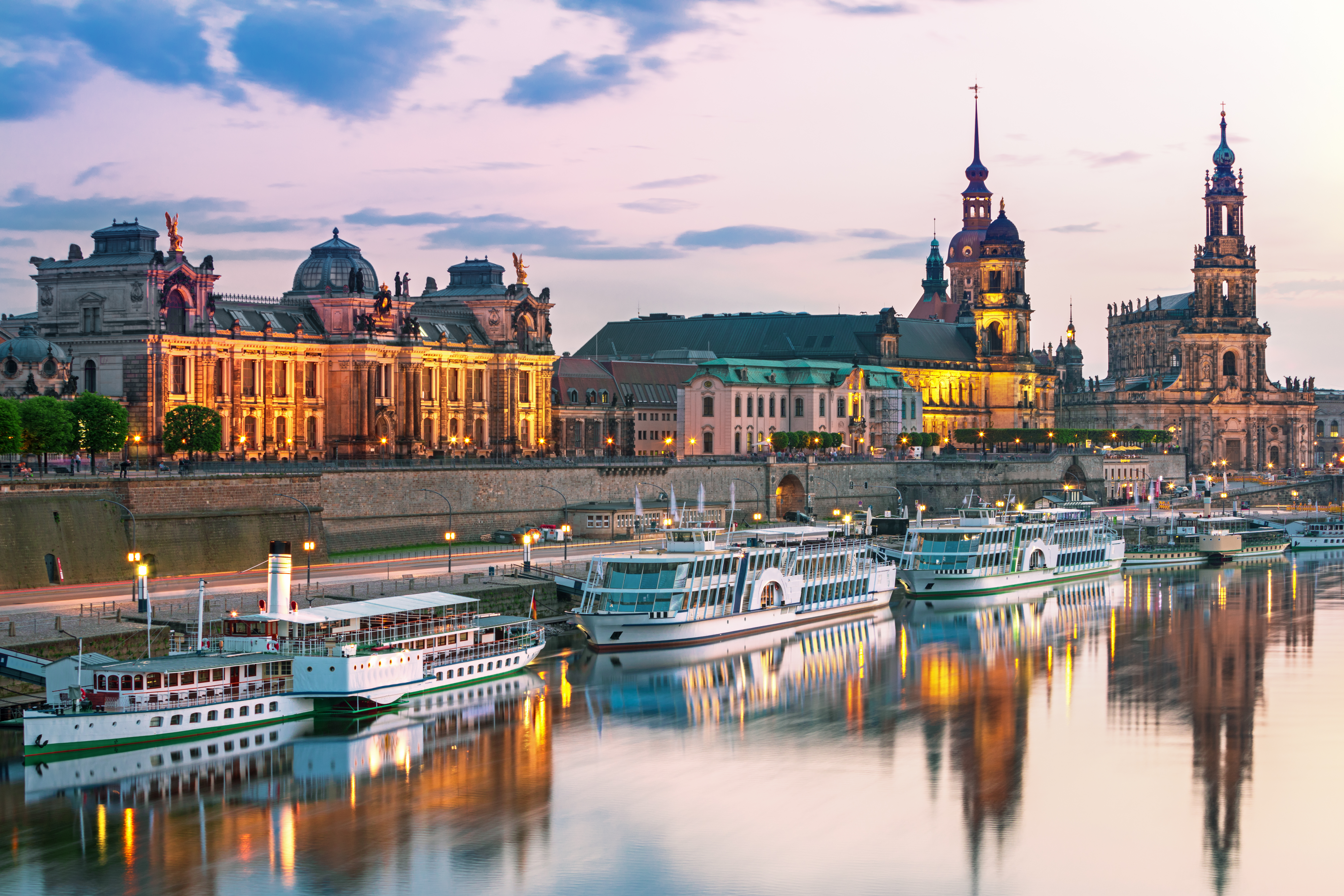 Idyllisk solnedgangsudsigt over Dresdens skyline med Augustus-broen og historiske bygninger spejlende sig i Elbens rolige vand i Sachsen