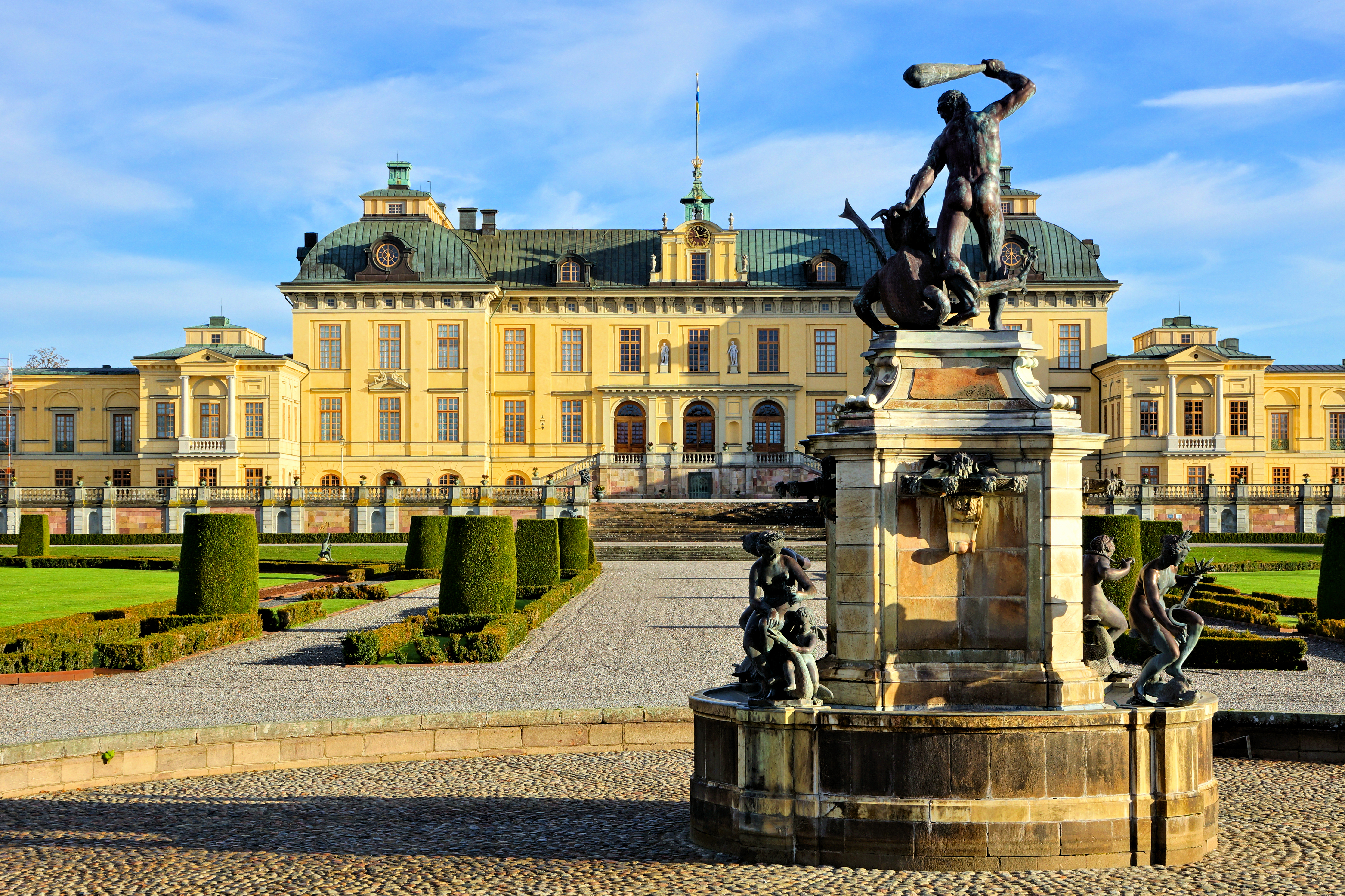 Smukke Drottningholm Slot med barok fontæne og skulpturer omgivet af grønne haver i Sverige