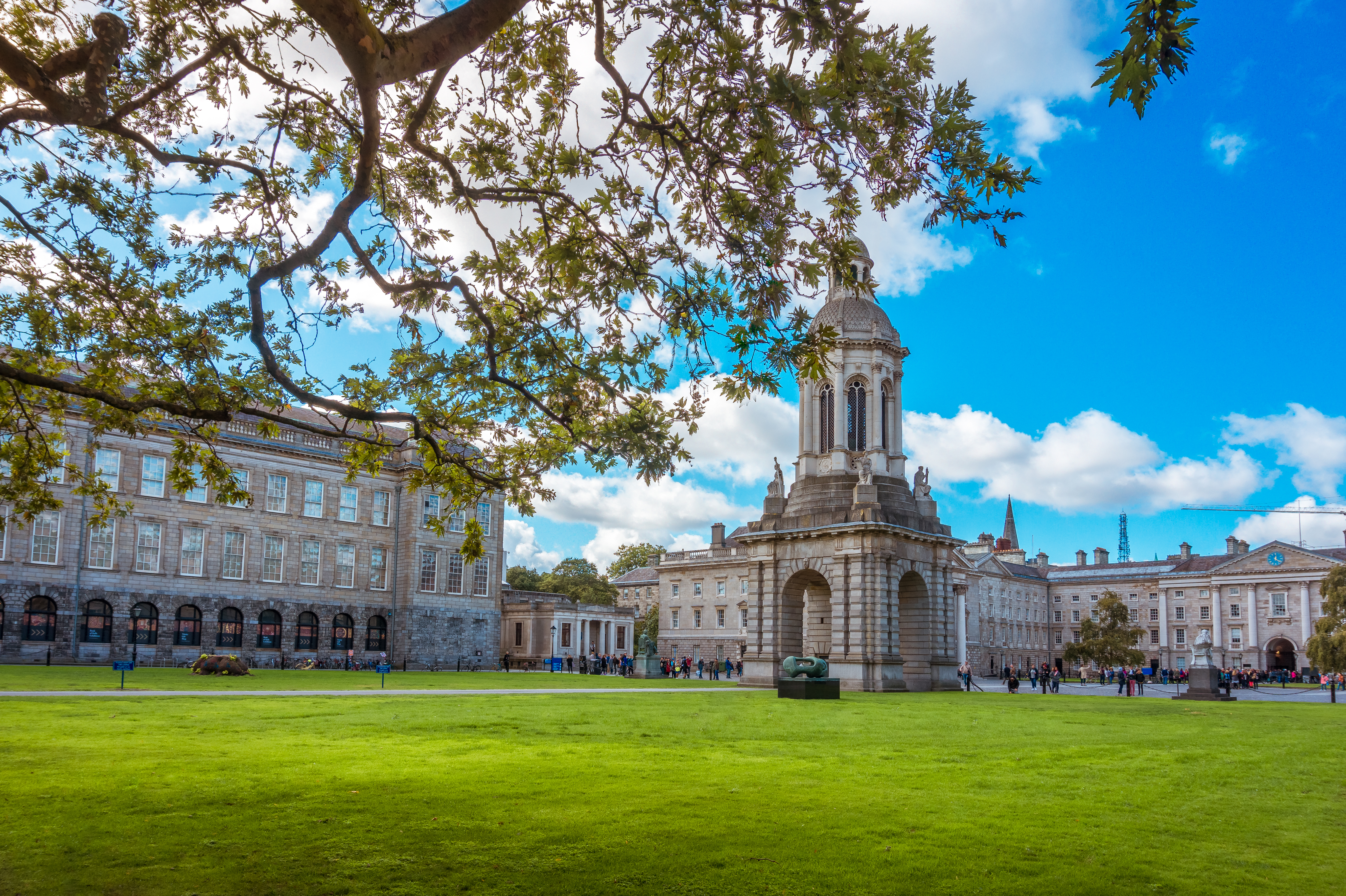 Det berømte Campanile-tårn på Trinity College Dublin omgivet af grønne plæner og historiske bygninger på en smuk sommerdag i Dublin, Irland