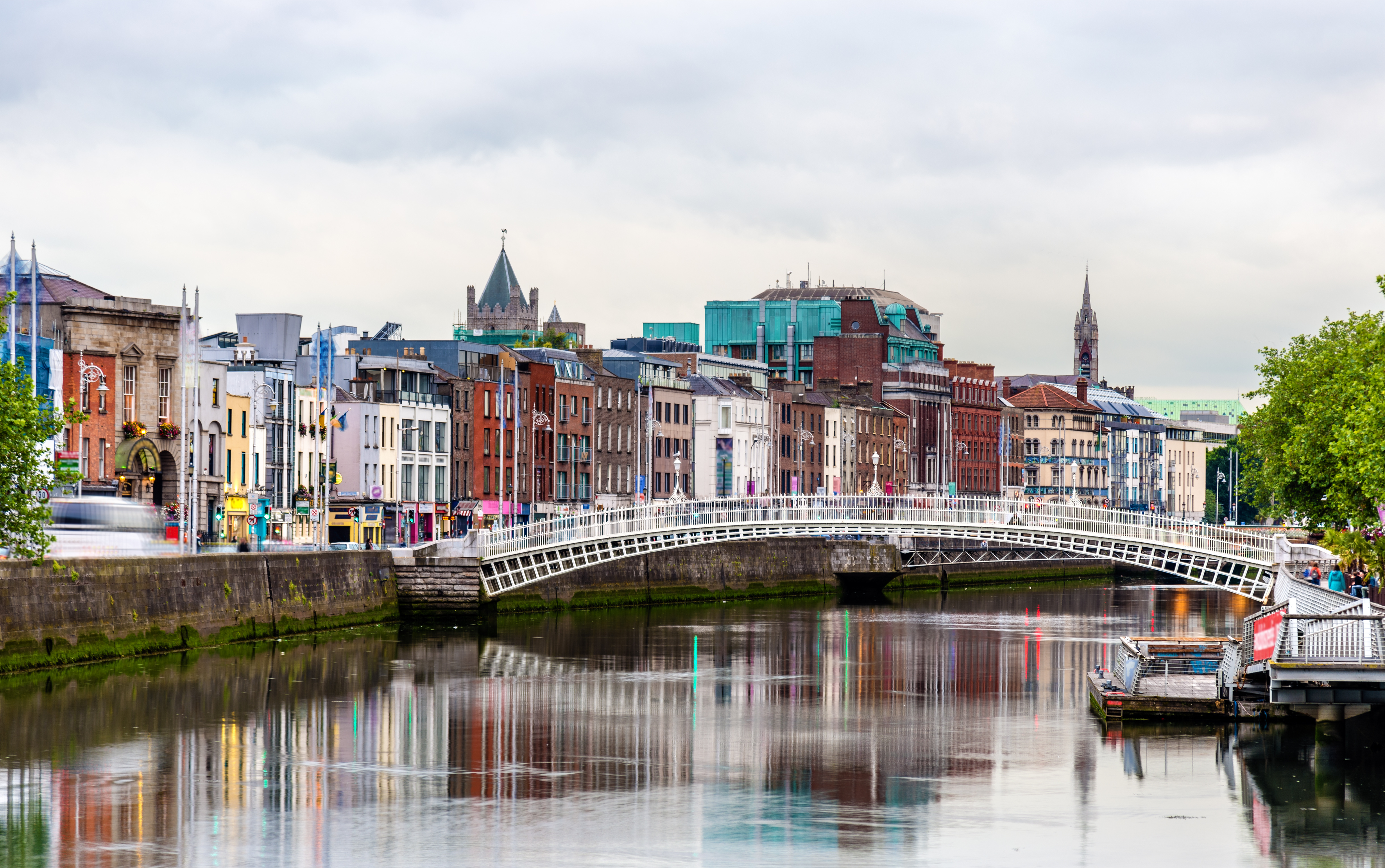 Historisk Ha'penny Bridge over River Liffey med Dublins farverige bybillede i baggrunden, Irland
