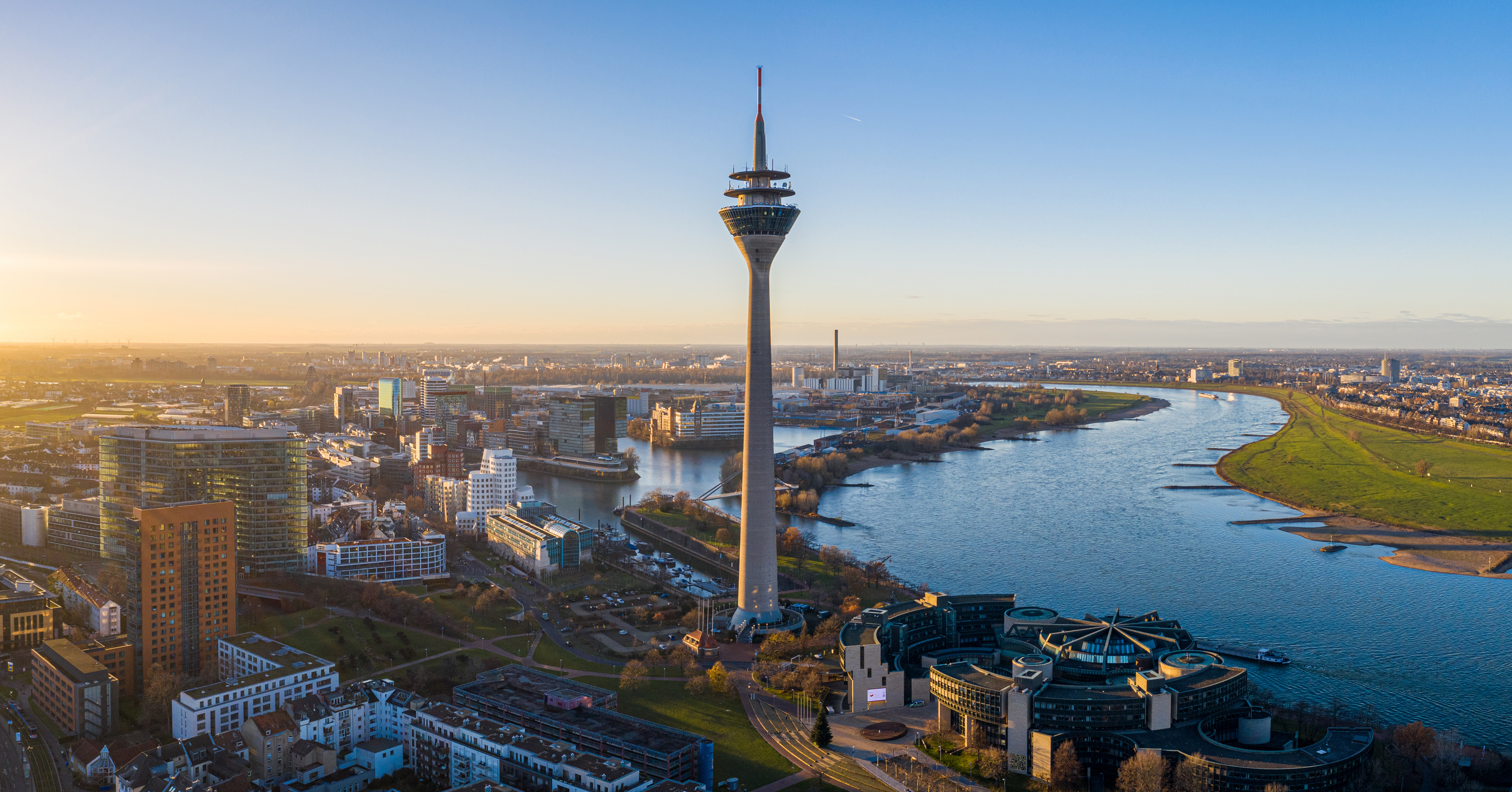 Fantastisk luftfoto af Düsseldorf ved solnedgang med det kendte Rhintårn og den brede Rhinen