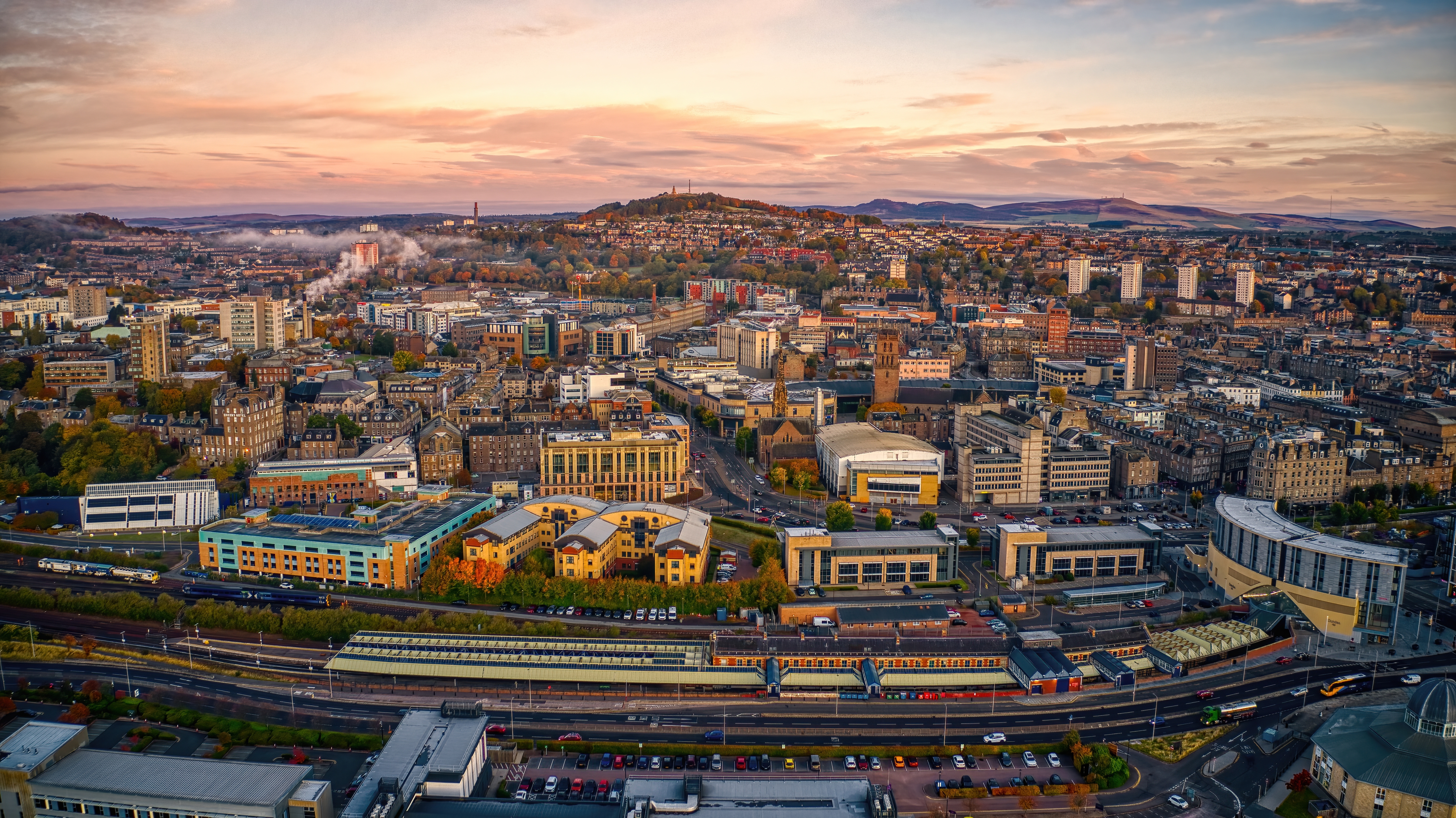 Luftfoto af Dundees bycenter i efterårsstemning ved solnedgang, Skotland, med Dundee Law og jernbanestationen i baggrunden