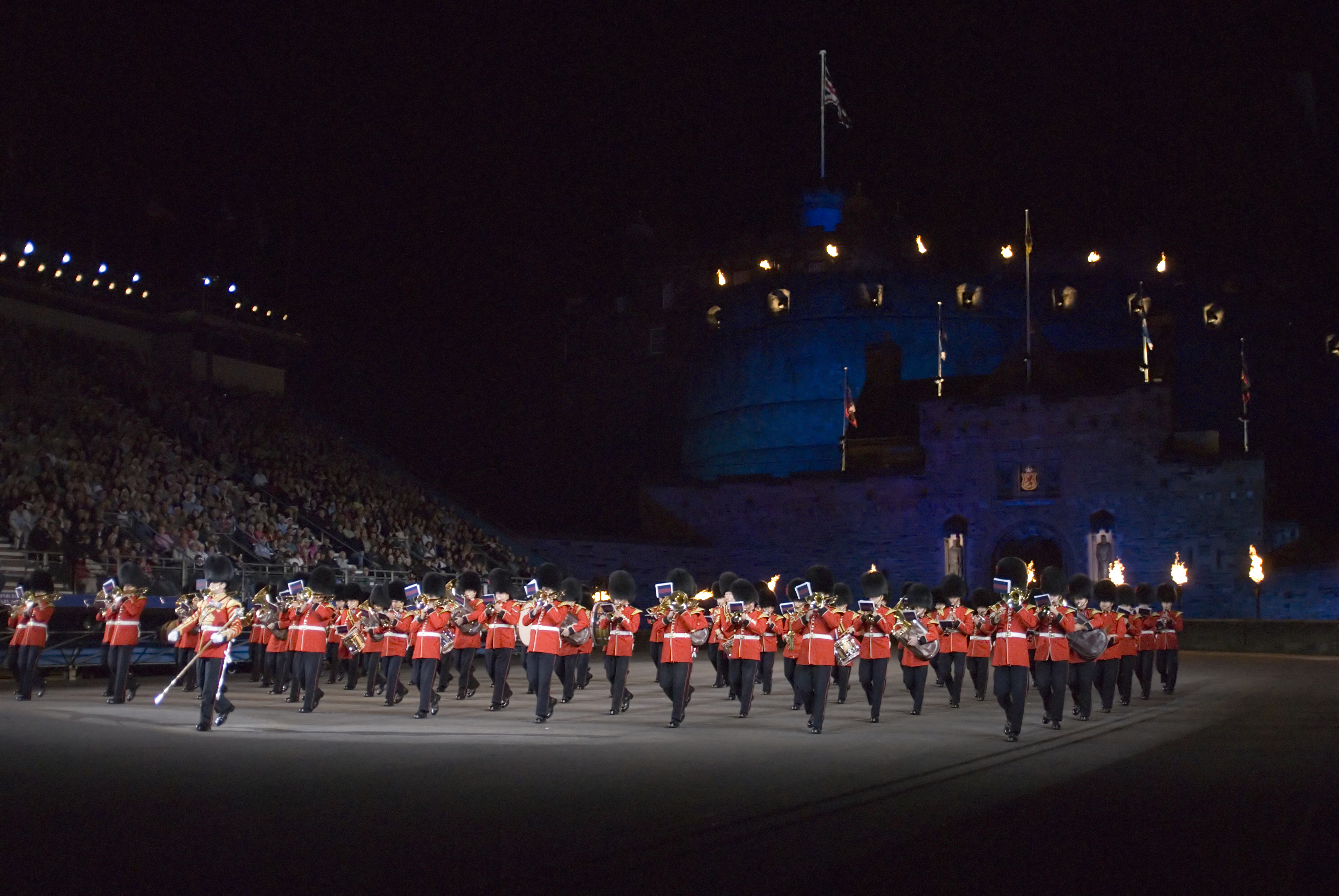 Imponerende natparade med Scots Guards ved Edinburgh Military Tattoo med det oplyste slot som baggrund