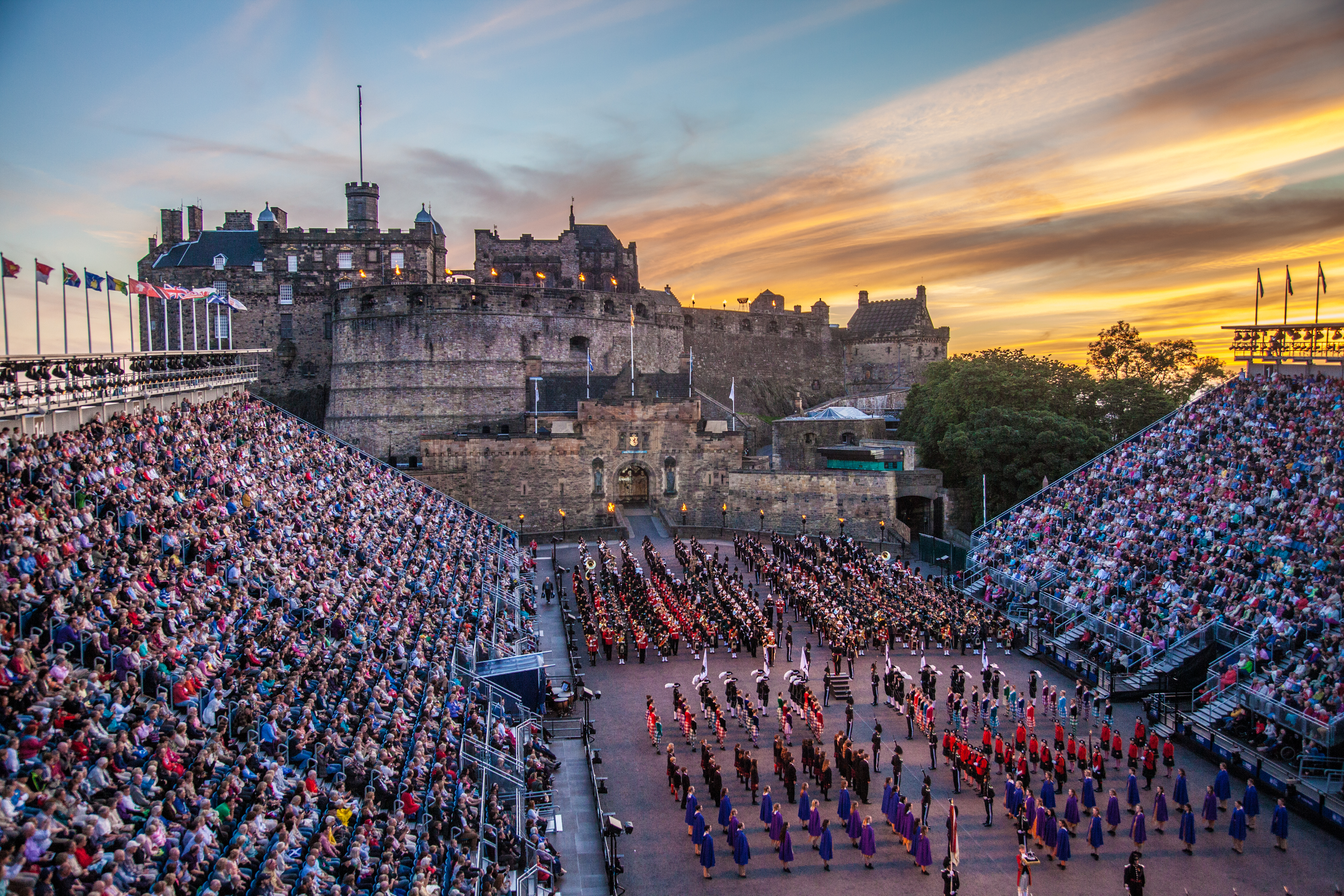 Traditionel skotsk Military Tattoo opvisning med marsjerende bands under aftenhimlen ved Edinburgh slot