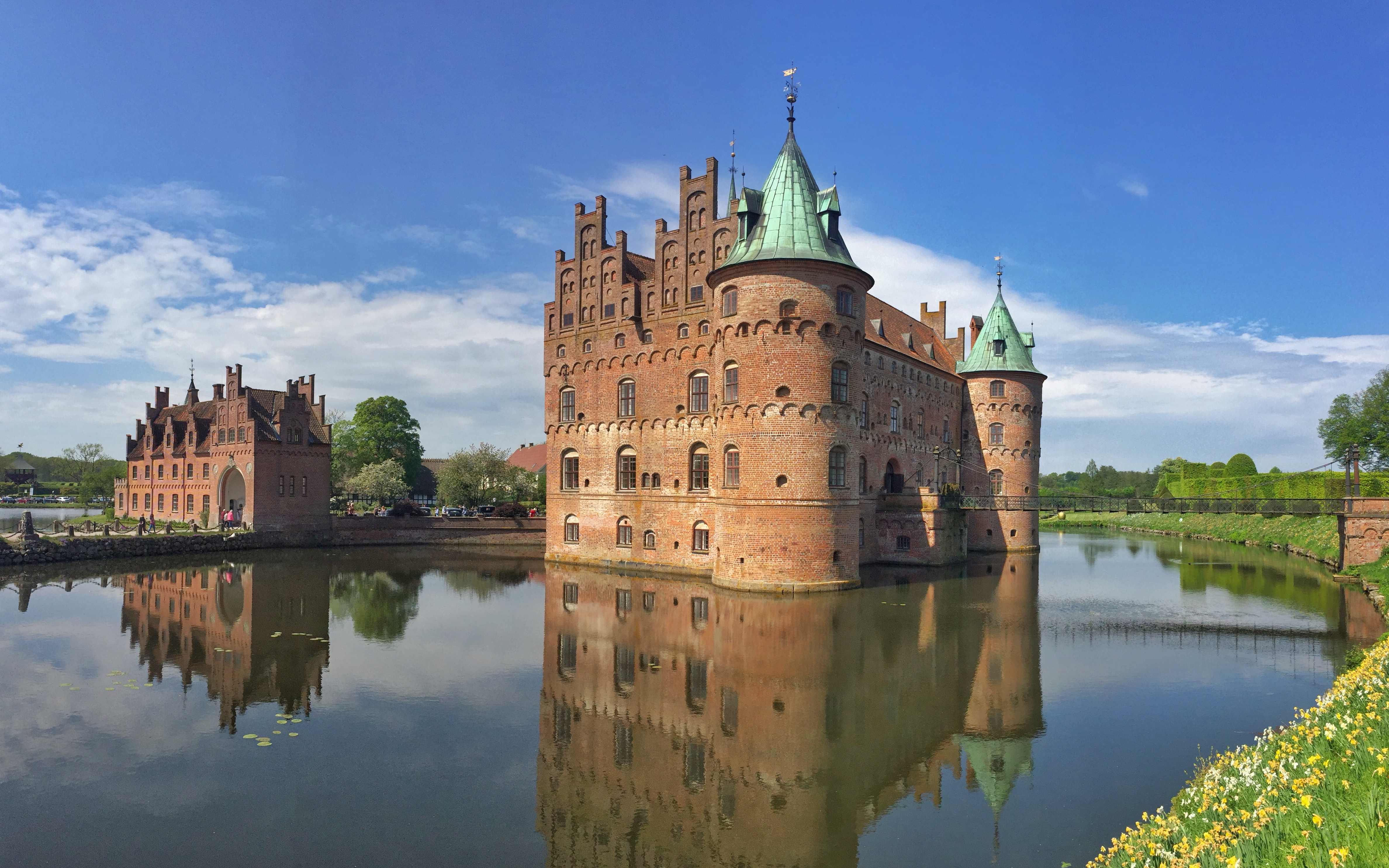Det smukke Egeskov vandslot med kobbertårne spejlet i voldgraven på en klar dag i Danmark