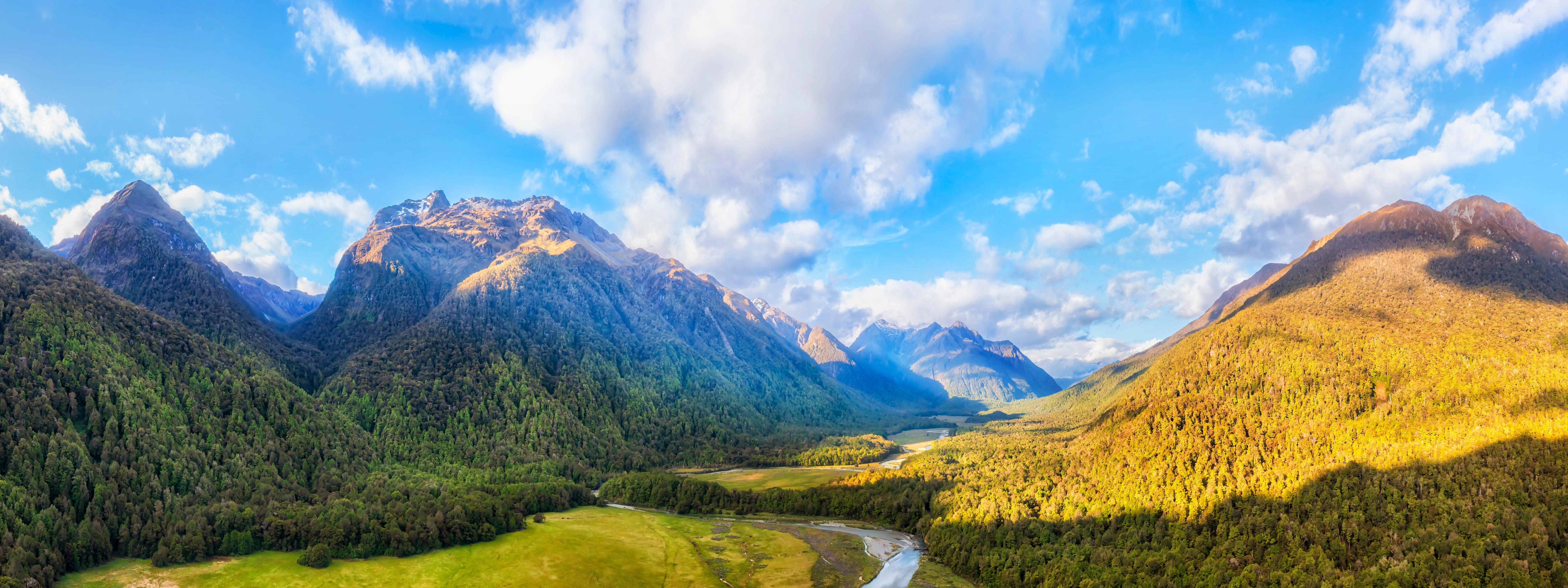Naturskøn luftpanorama over Eglinton Dalen og floden i Fiordland National Park på New Zealands sydø med sneklædte bjergtinder