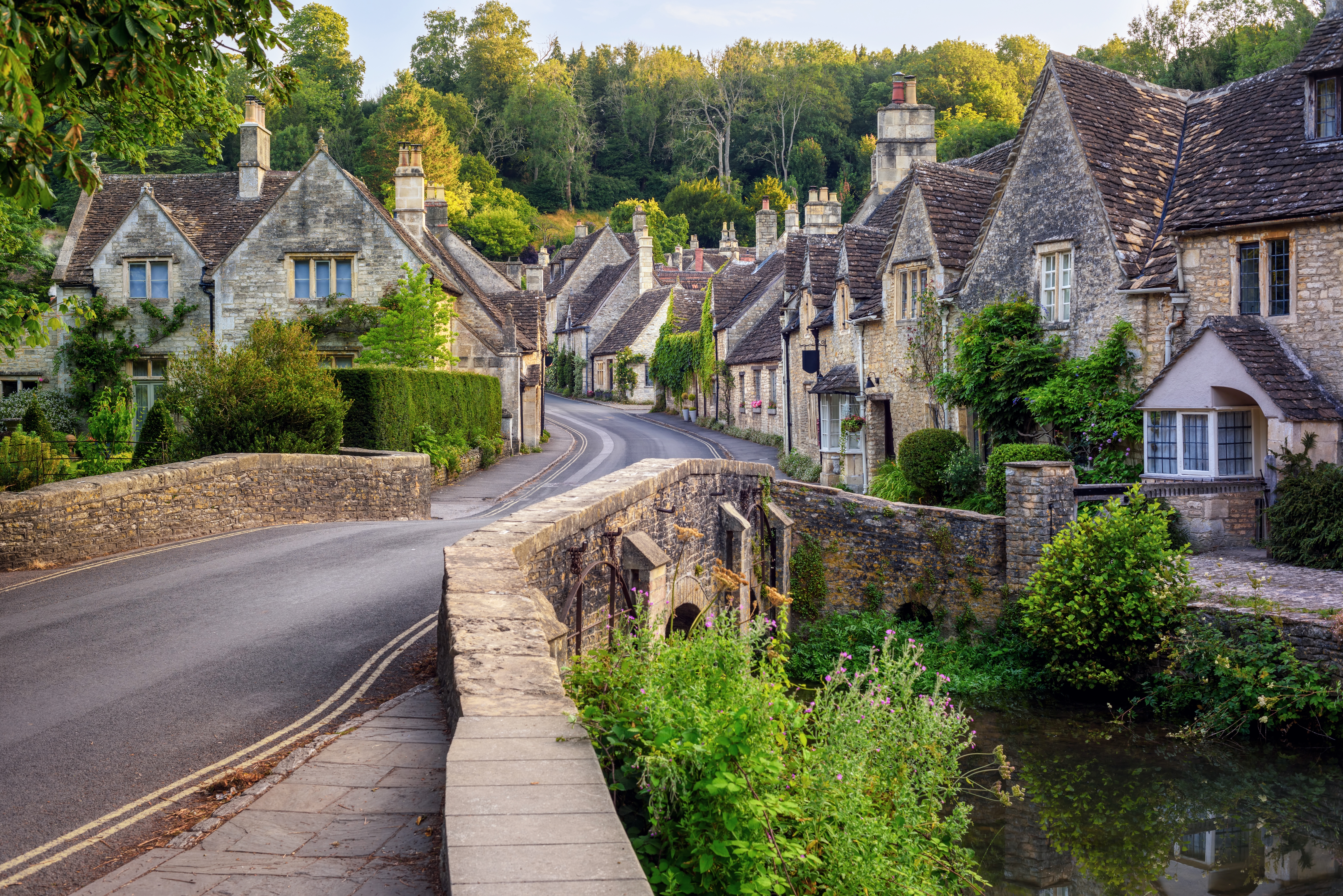 Charmerende Castle Combe i Cotswolds, England med gammel stenebro over flod og traditionelle engelske cottages
