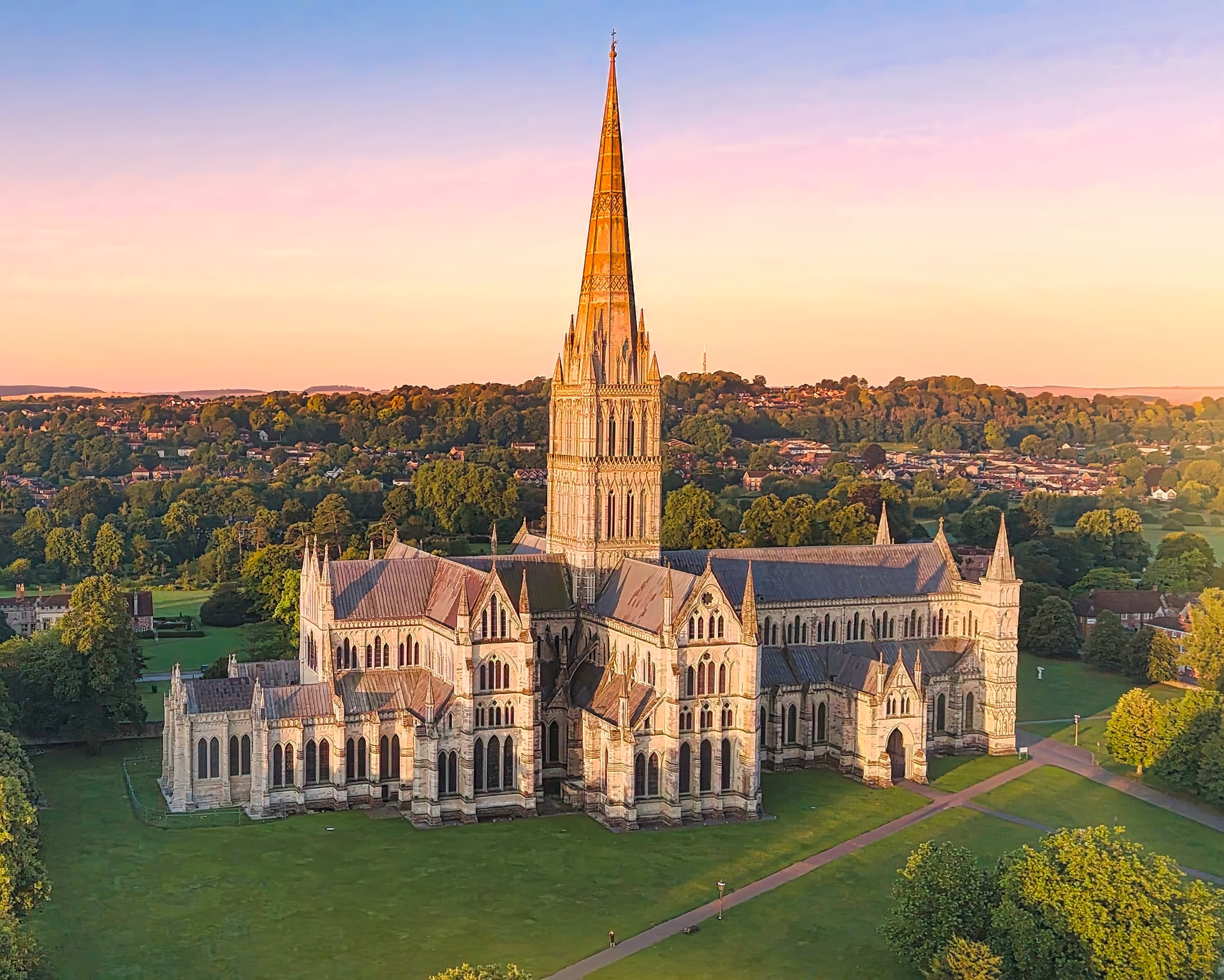 Spektakulært luftbillede af den berømte Salisbury Katedral i England badet i gyldent sollys, en perle af engelsk kulturarv