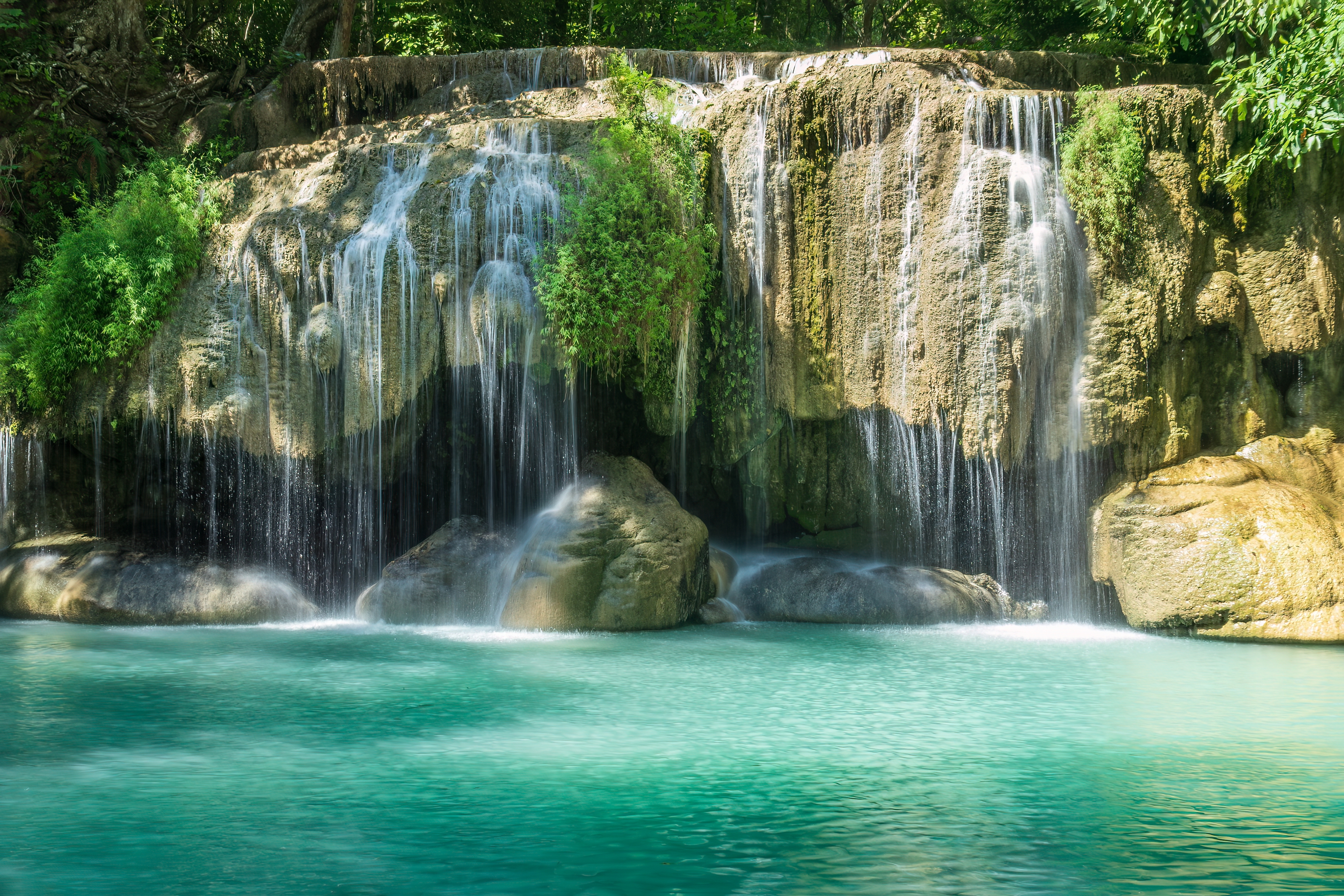 Erawan vandfald styrter ned over klipper til turkist naturpool i tæt jungle, Kanchanaburi Thailand