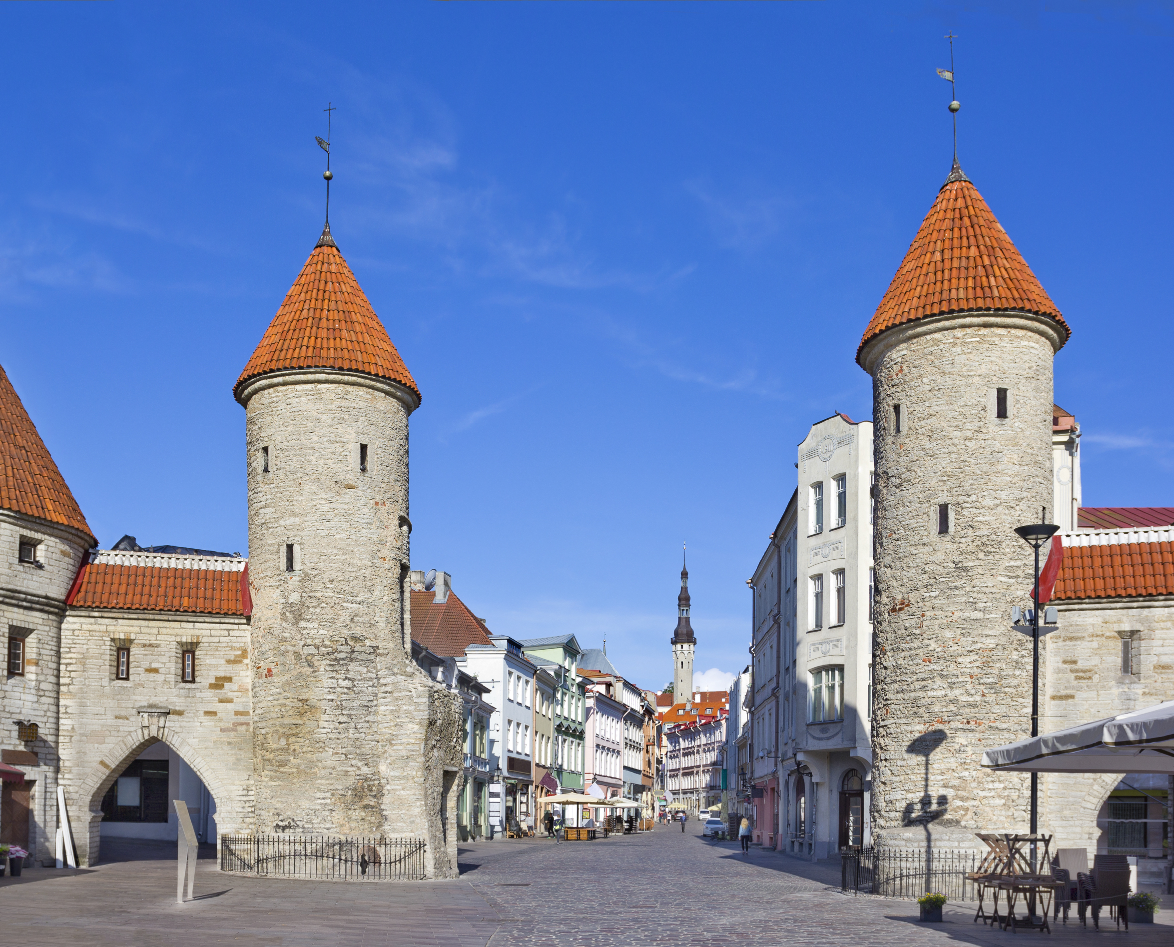 Ikoniske middelalderlige stentårne og byport i Tallinns historiske centrum med traditionelle bygninger og blå himmel