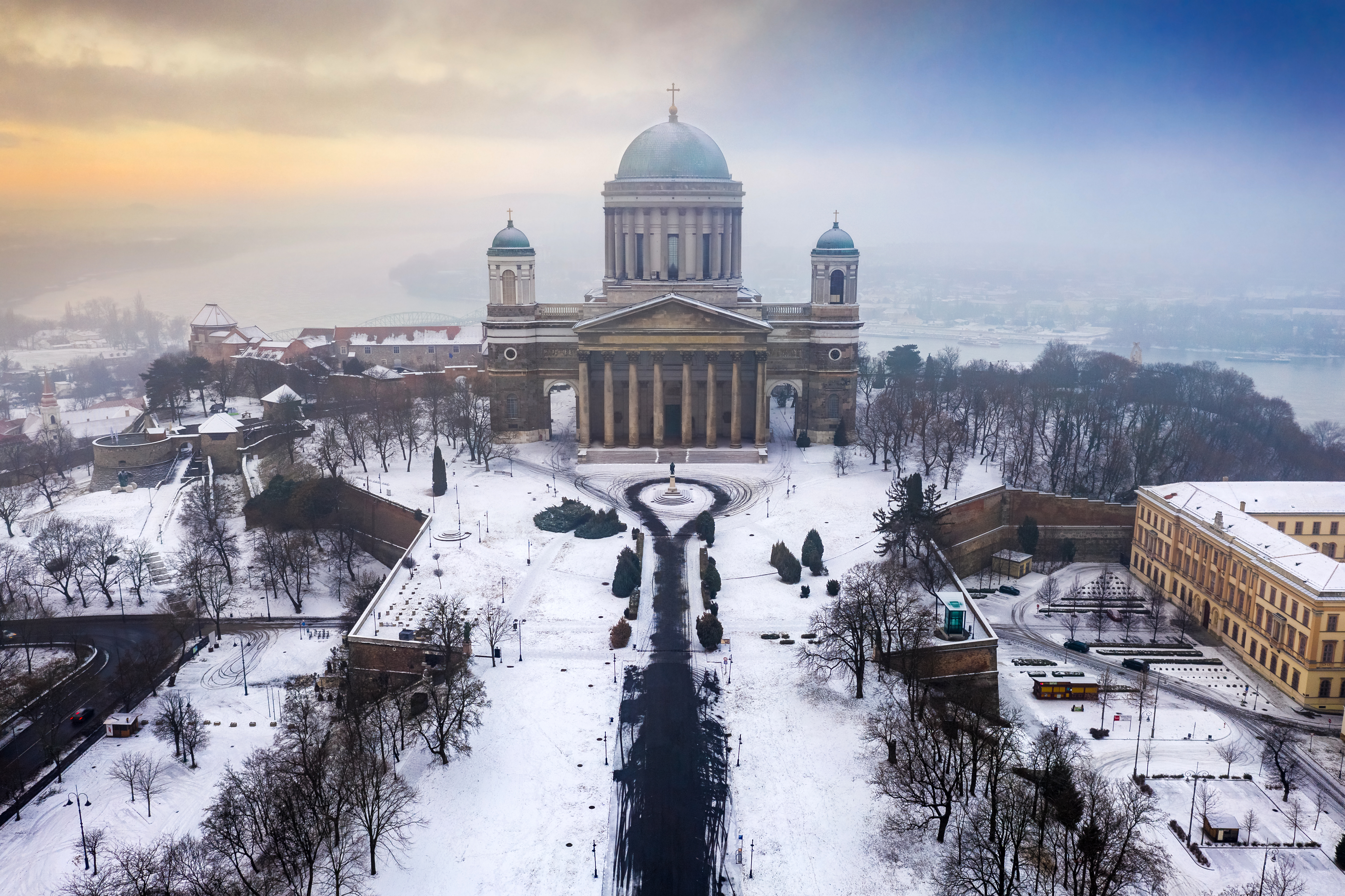 Smukt vinterlandskab med den ikoniske Esztergom Basilika i Ungarn set fra luften med Donau og tåge i baggrunden