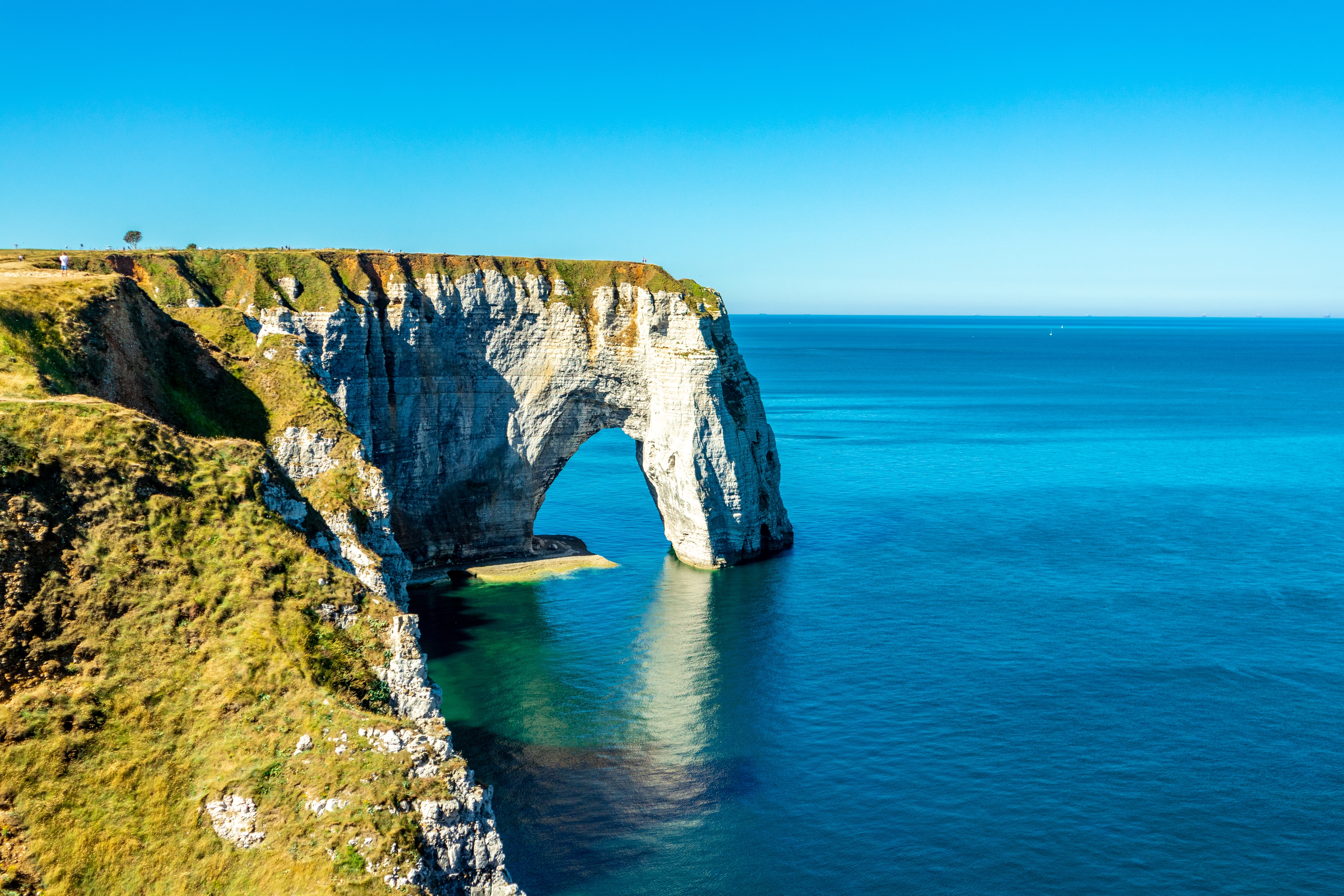 Dramatiske kridtklipper og naturlig stenbue ved Etretat på Alabastkysten i Normandiet med blåt hav