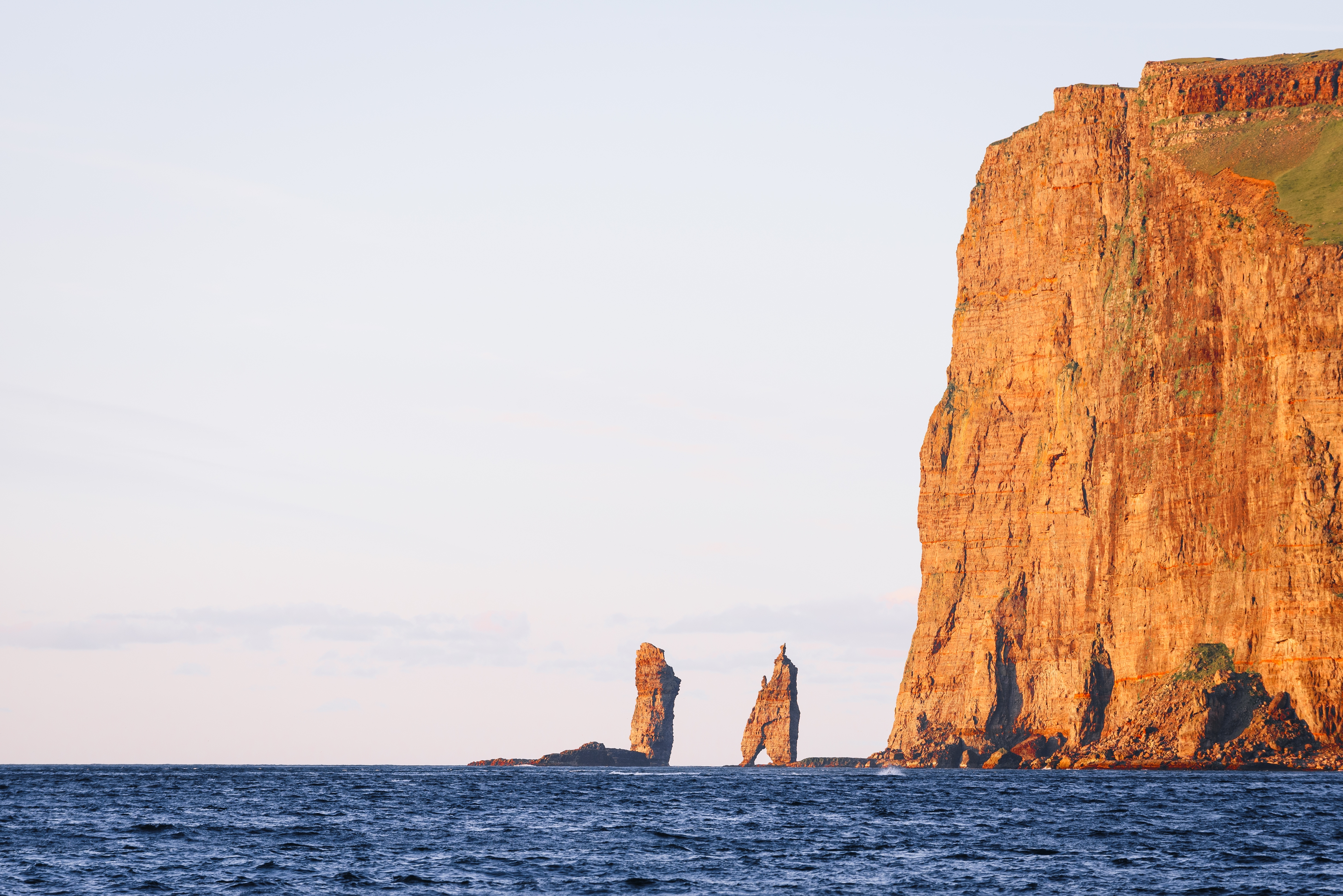 Storslået panorama over de ikoniske Risin og Kellingin klipper i havet ud for Færøerne, fotograferet fra den idylliske landsby Tjørnuvík