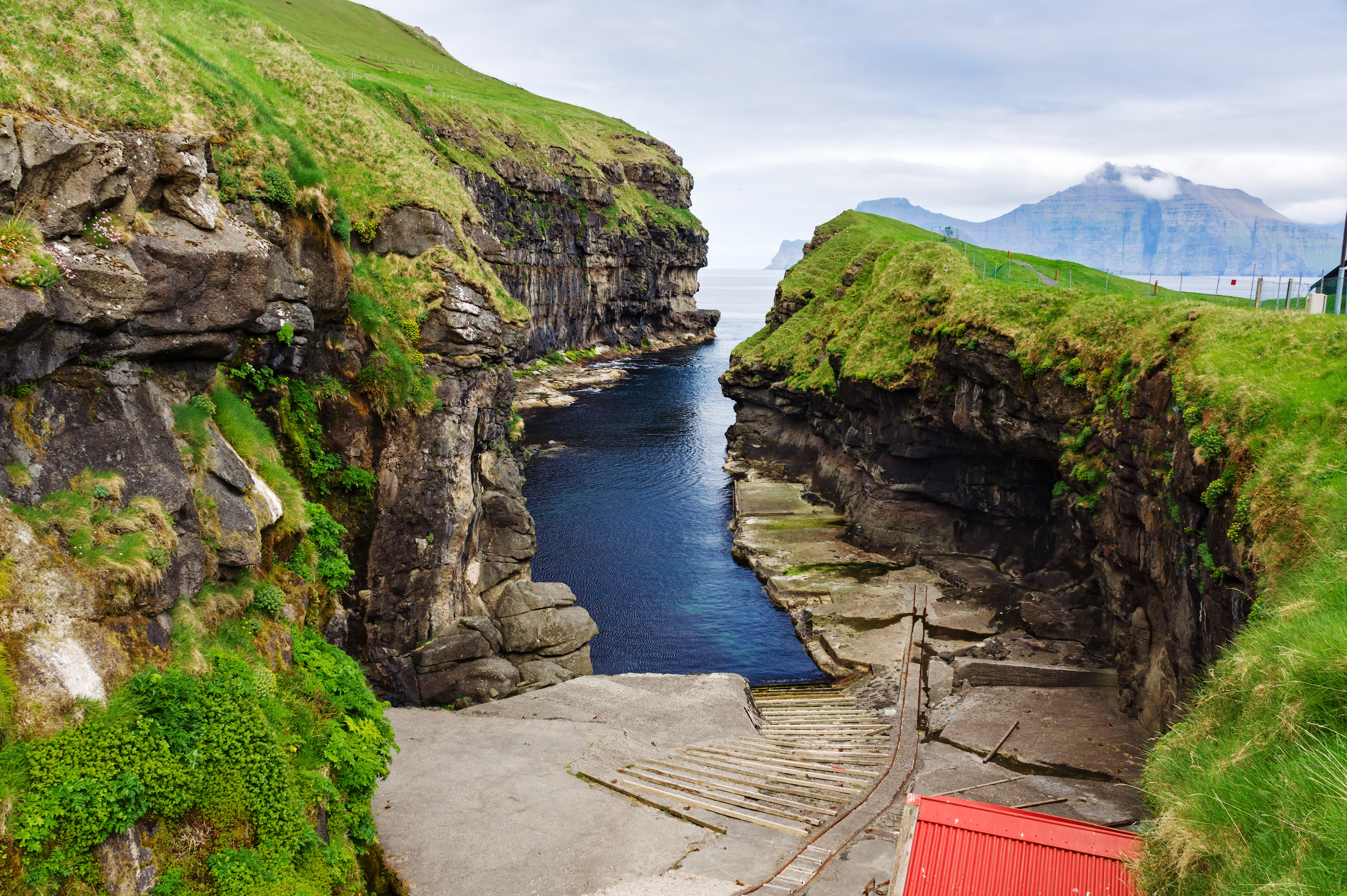 Bjerglandskab og naturhavn ved Gjógv på Færøerne med krystalklart atlanterhavsvand