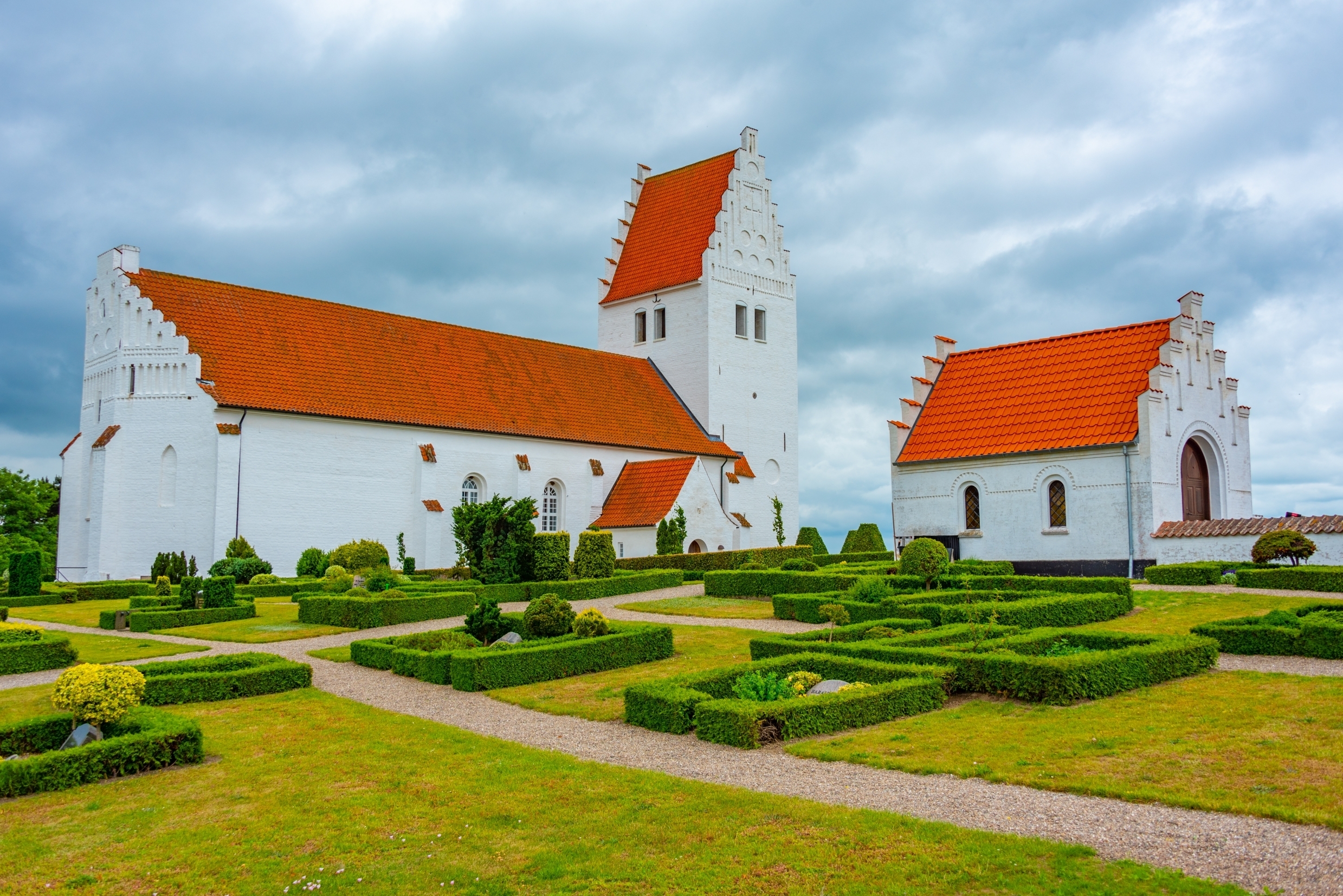 Fanefjord Kirke på Møn, en af Danmarks smukkeste middelalderkirker med hvide mure og præcist klippede hækanlæg