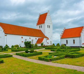 Fanefjord Kirke på Møn, en af Danmarks smukkeste middelalderkirker med hvide mure og præcist klippede hækanlæg