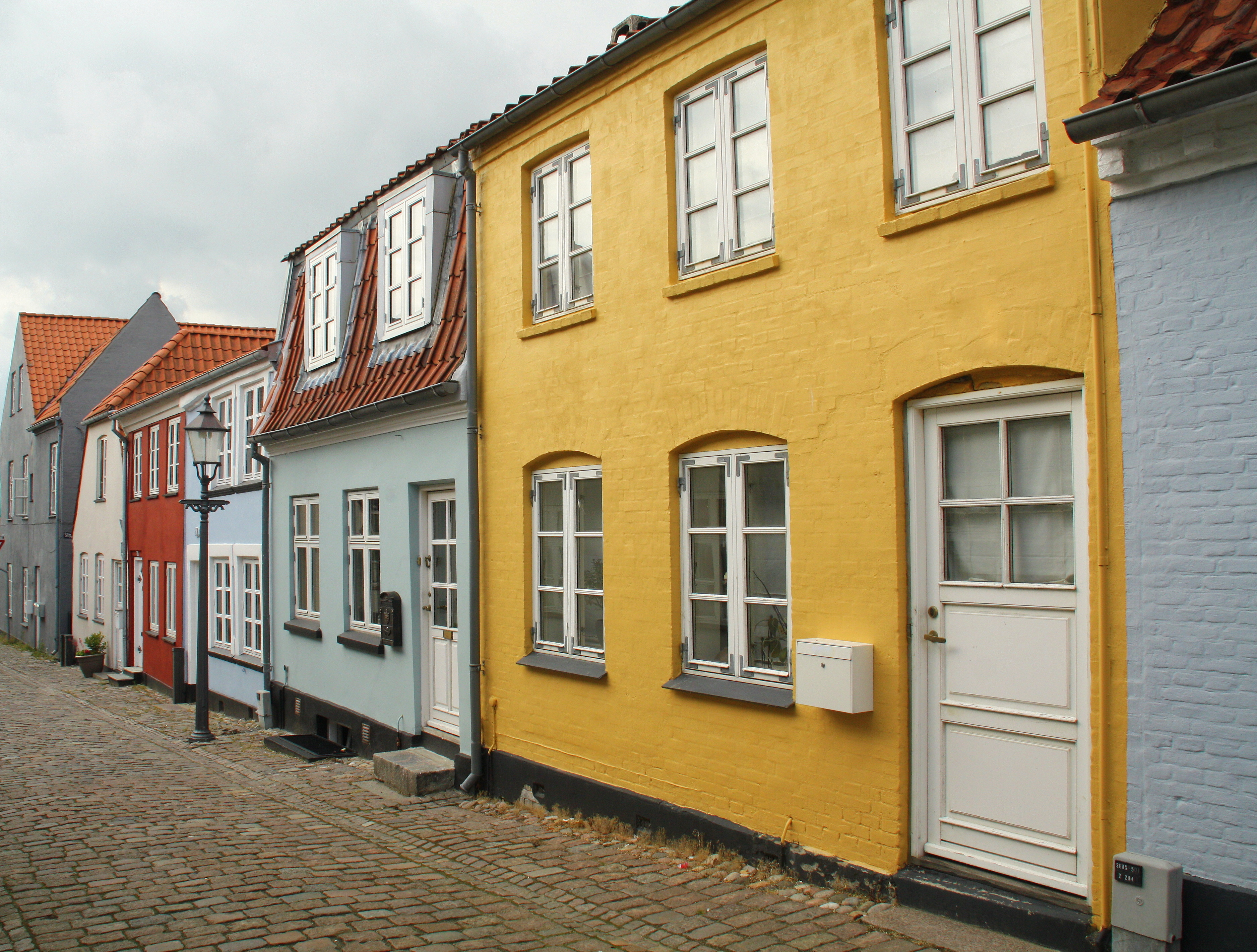 Hyggelig brolagt gade med gule, blå og røde historiske huse i Nykøbing Falster på øen Falster