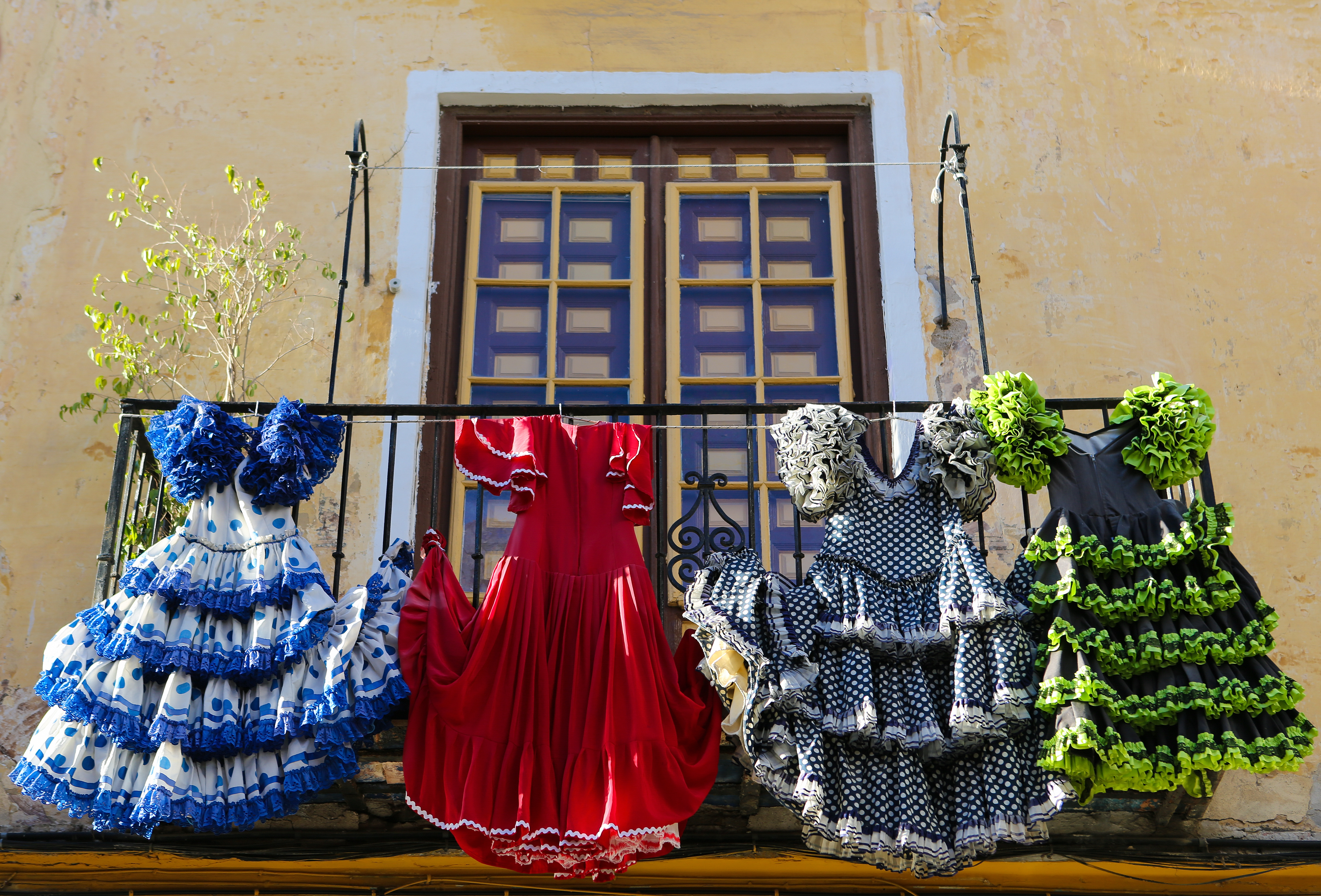 Traditionelle flamenco-kjoler i strålende farver udstillet på et hus i Malaga, Andalusien, repræsenterer Spaniens levende kulturarv