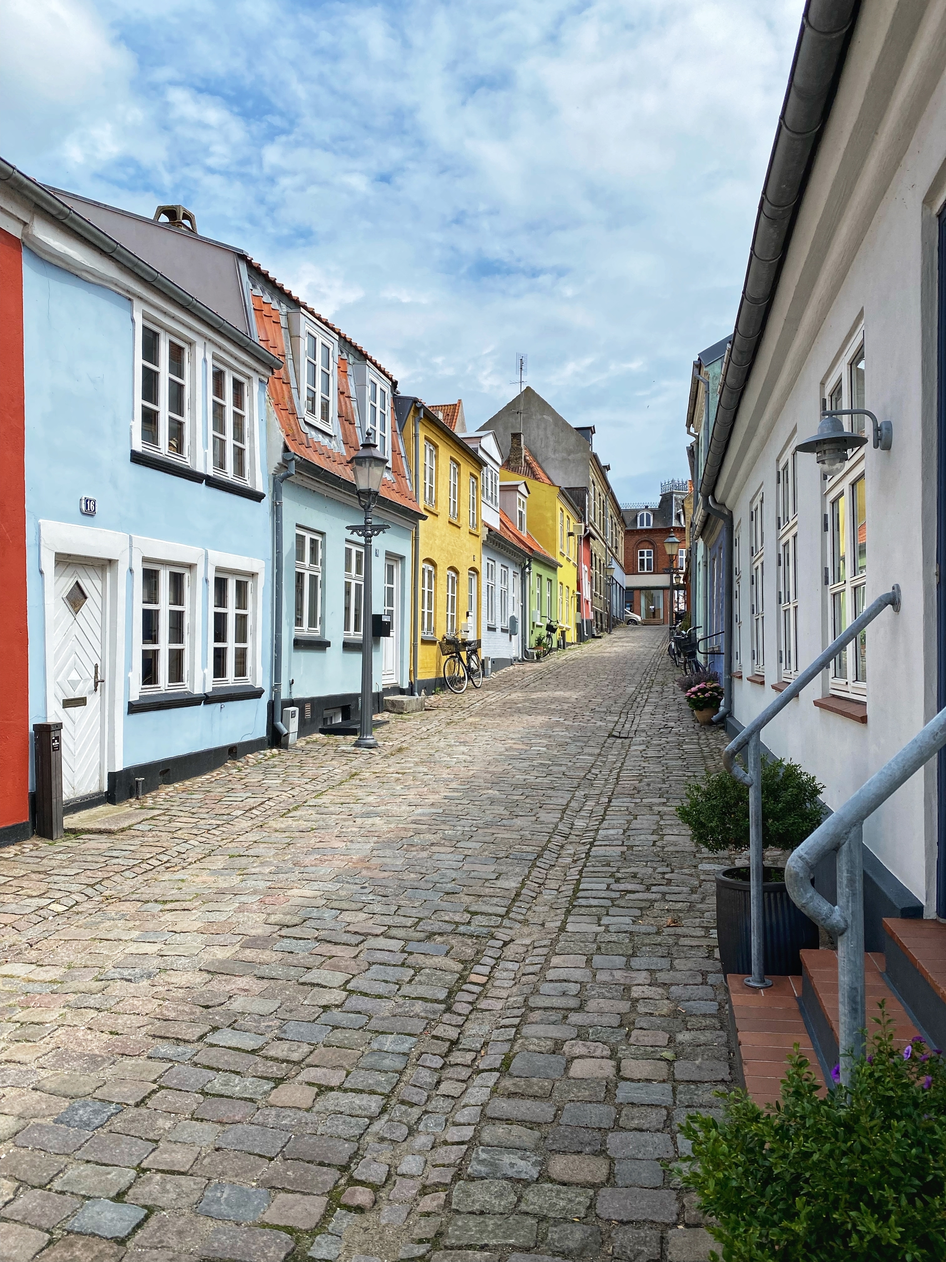 Farverige historiske huse langs brolagt gade i Nykøbing Falster, Danmark