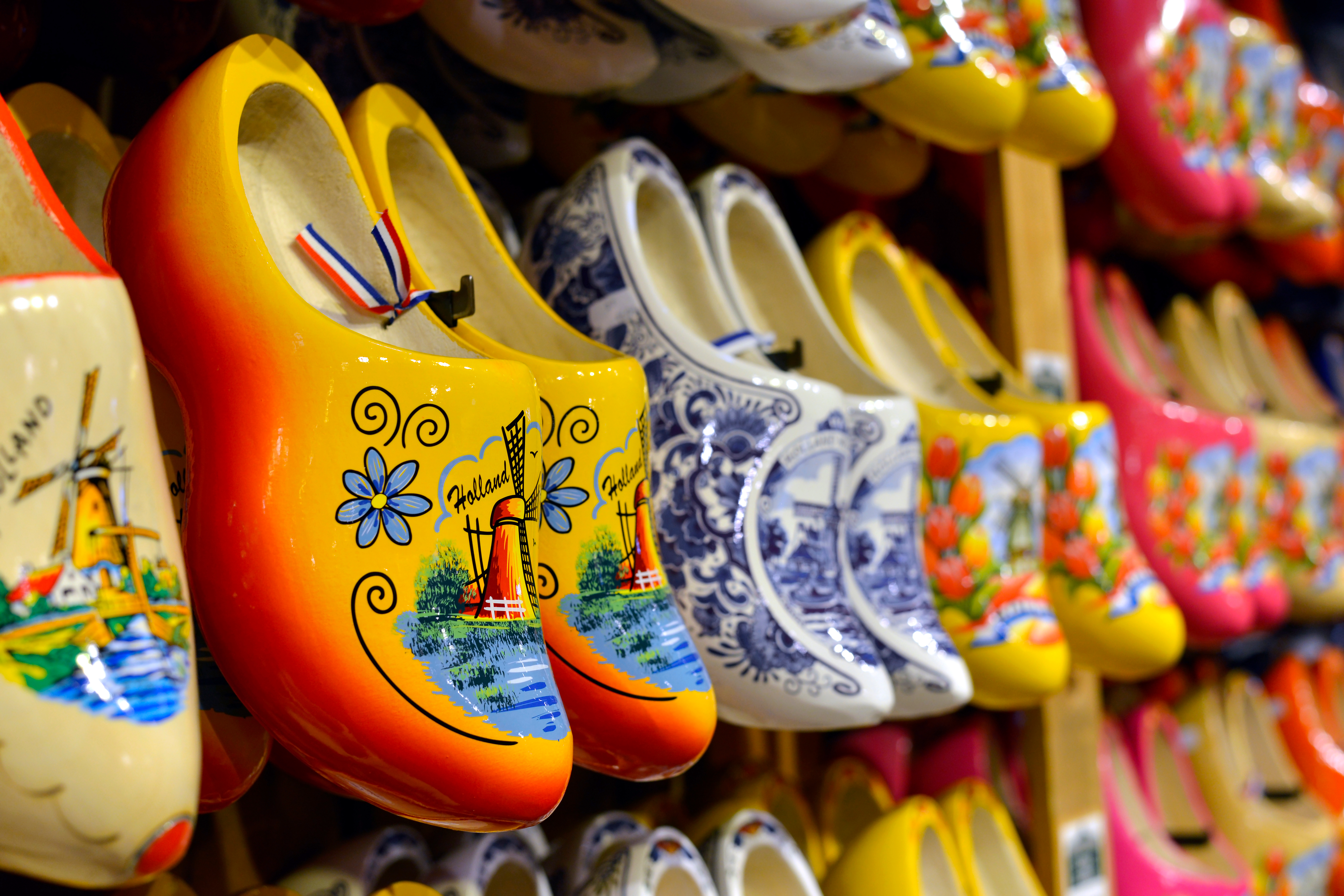 Smukke farverige træsko fra Holland opstillet på hylder med traditionelle hollandske motiver som vindmøller og tulipaner
