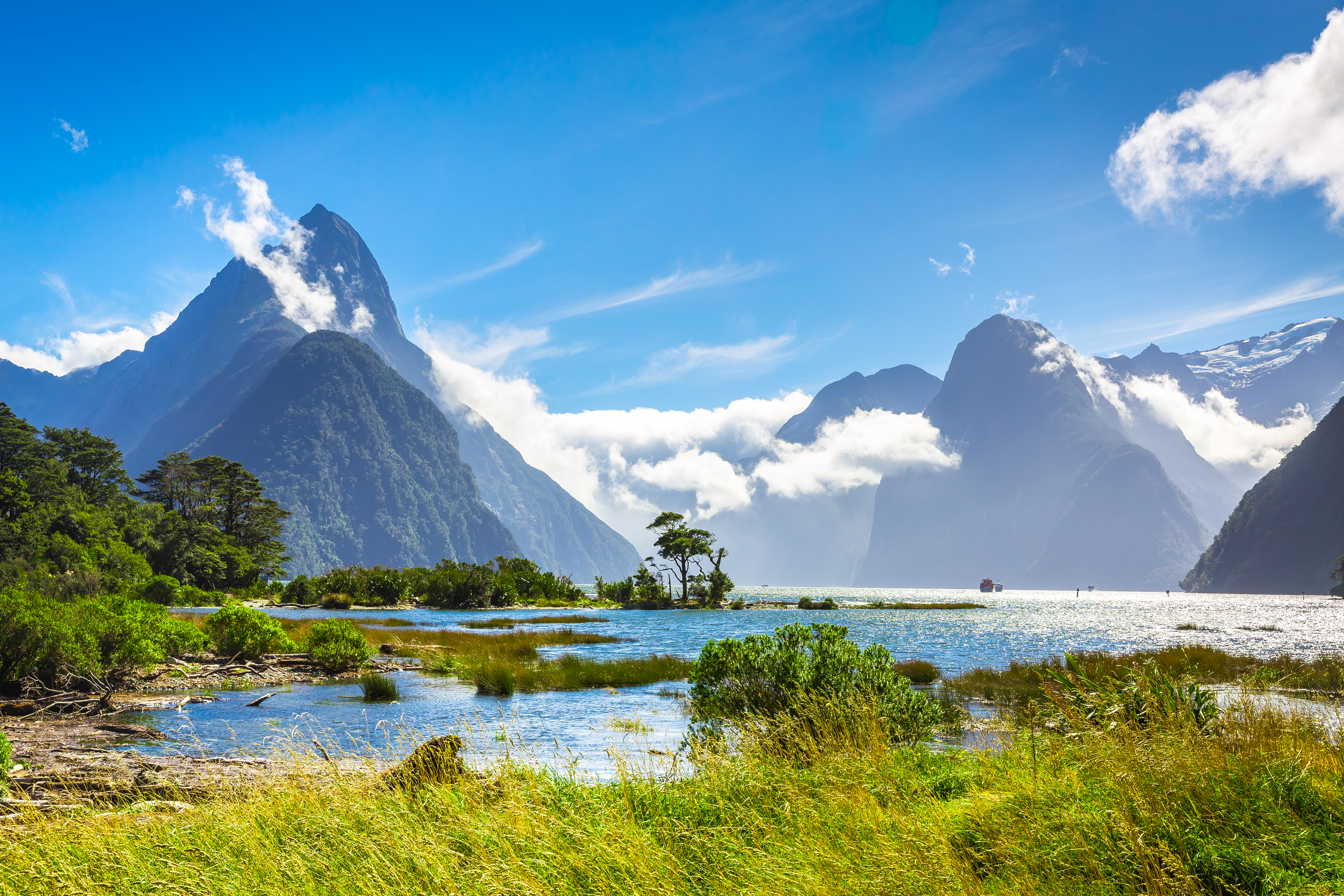 Smukt landskab ved Milford Sound i Fiordland National Park, New Zealand, med det majestætiske Mitre Peak der stikker op gennem skyerne over den rolige fjord