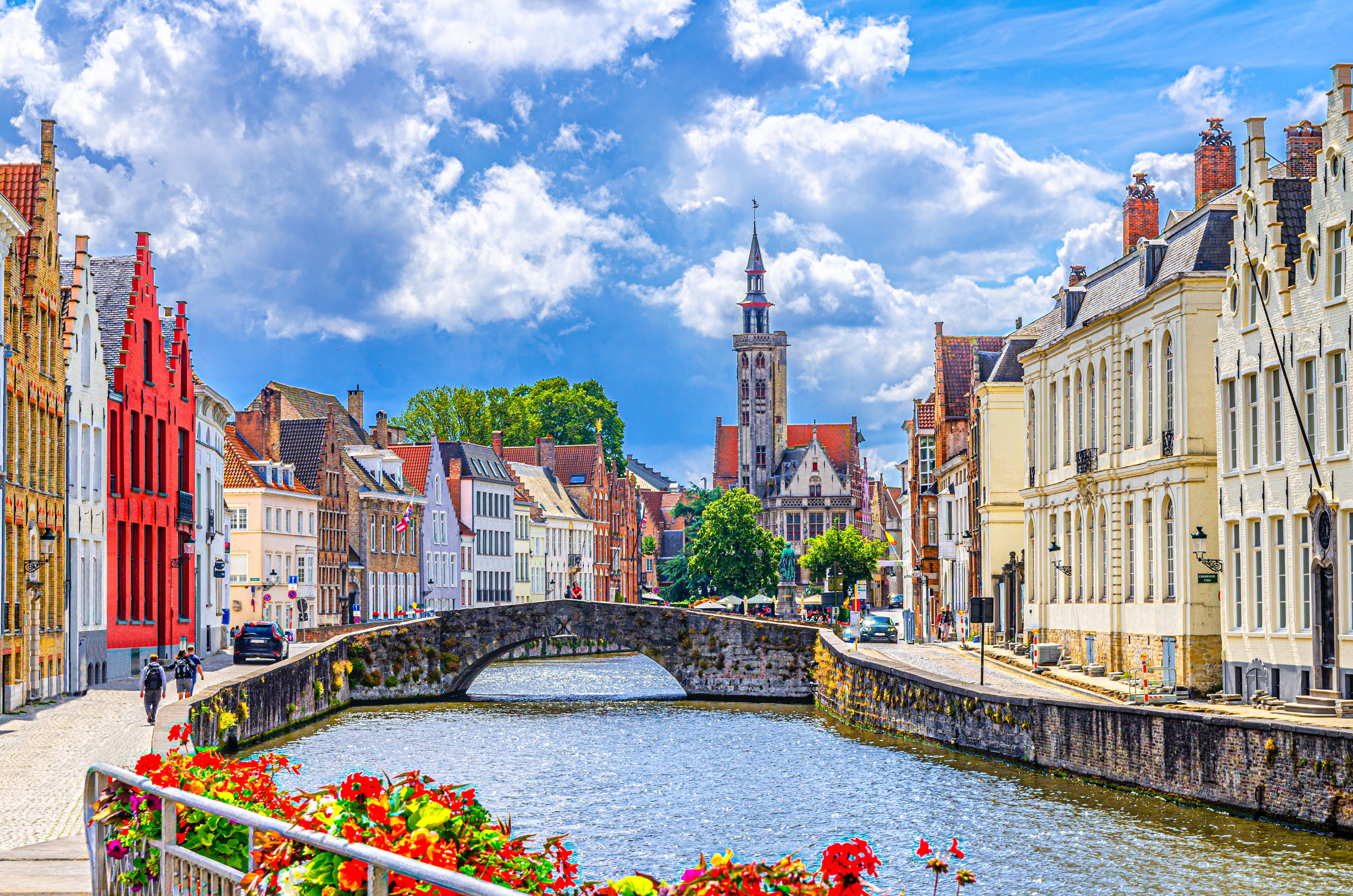 Betagende billede af Brugges UNESCO-beskyttede bymidte med den spejlblanke Spiegelrei-kanal, det historiske Poortersloge-tårn og Kongebroen omgivet af farverige middelalderlige bygninger