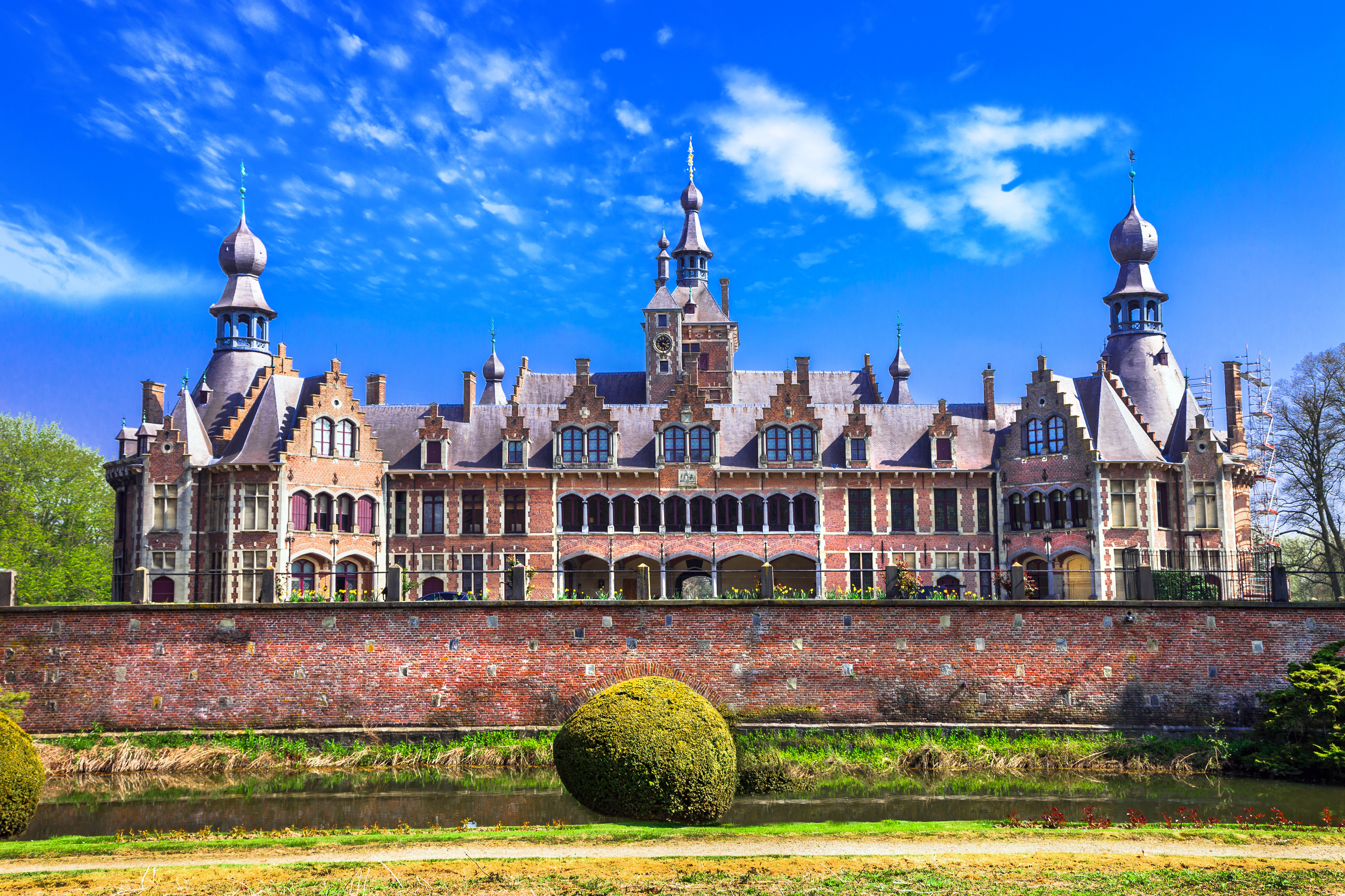 Det maleriske Ooidonk Slot i Deinze, Østflandern - et romantisk middelalderslot med karakteristiske tårne og spir, omgivet af idyllisk natur i det nordlige Belgien