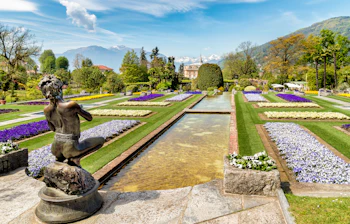 Formelle haver med statue og farverige blomster ved Villa Taranto i Piedmont, Italien