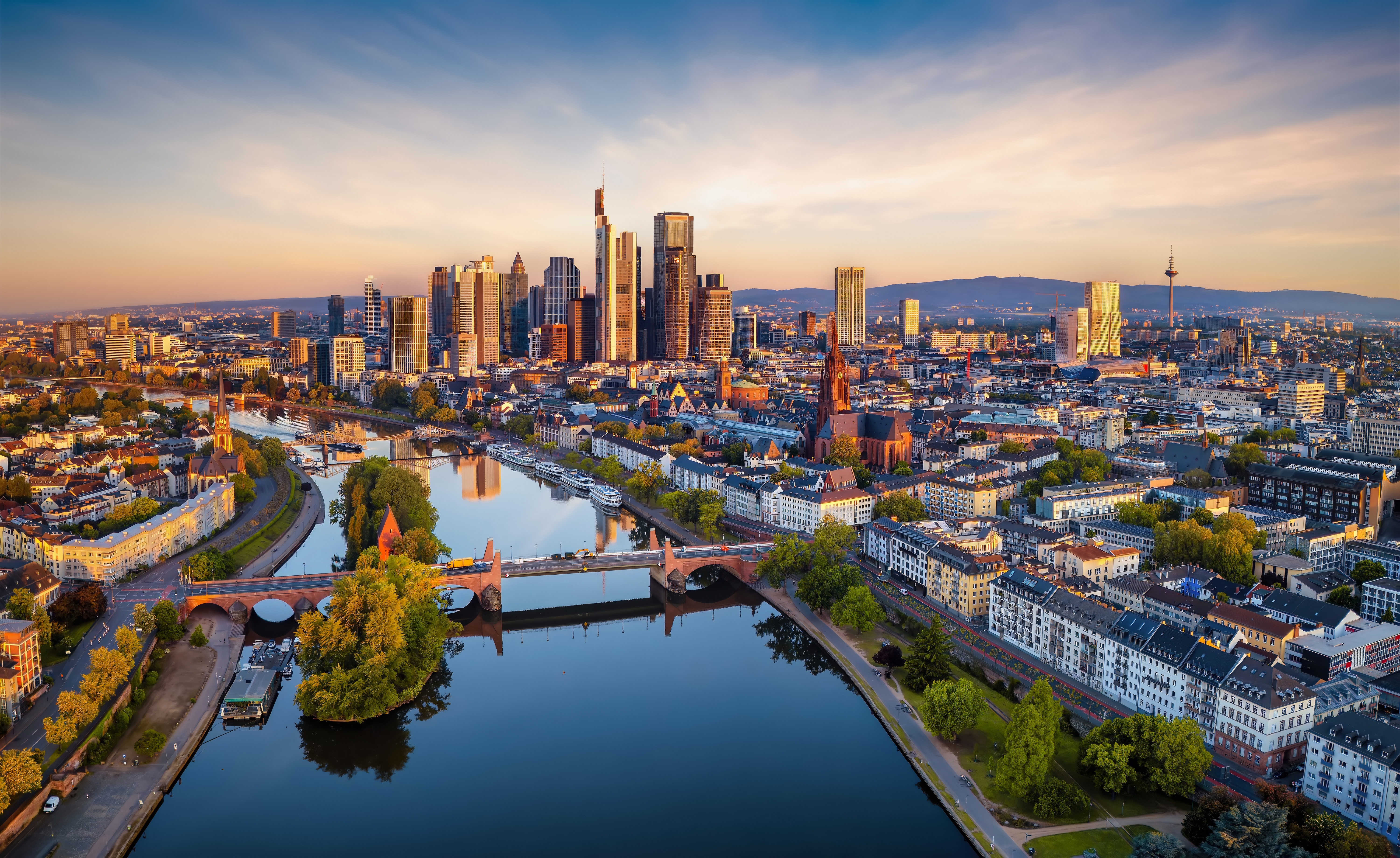 Spektakulær udsigt over Frankfurts skyline med moderne skyskrabere og floden Main i gyldent morgenlys, Tyskland