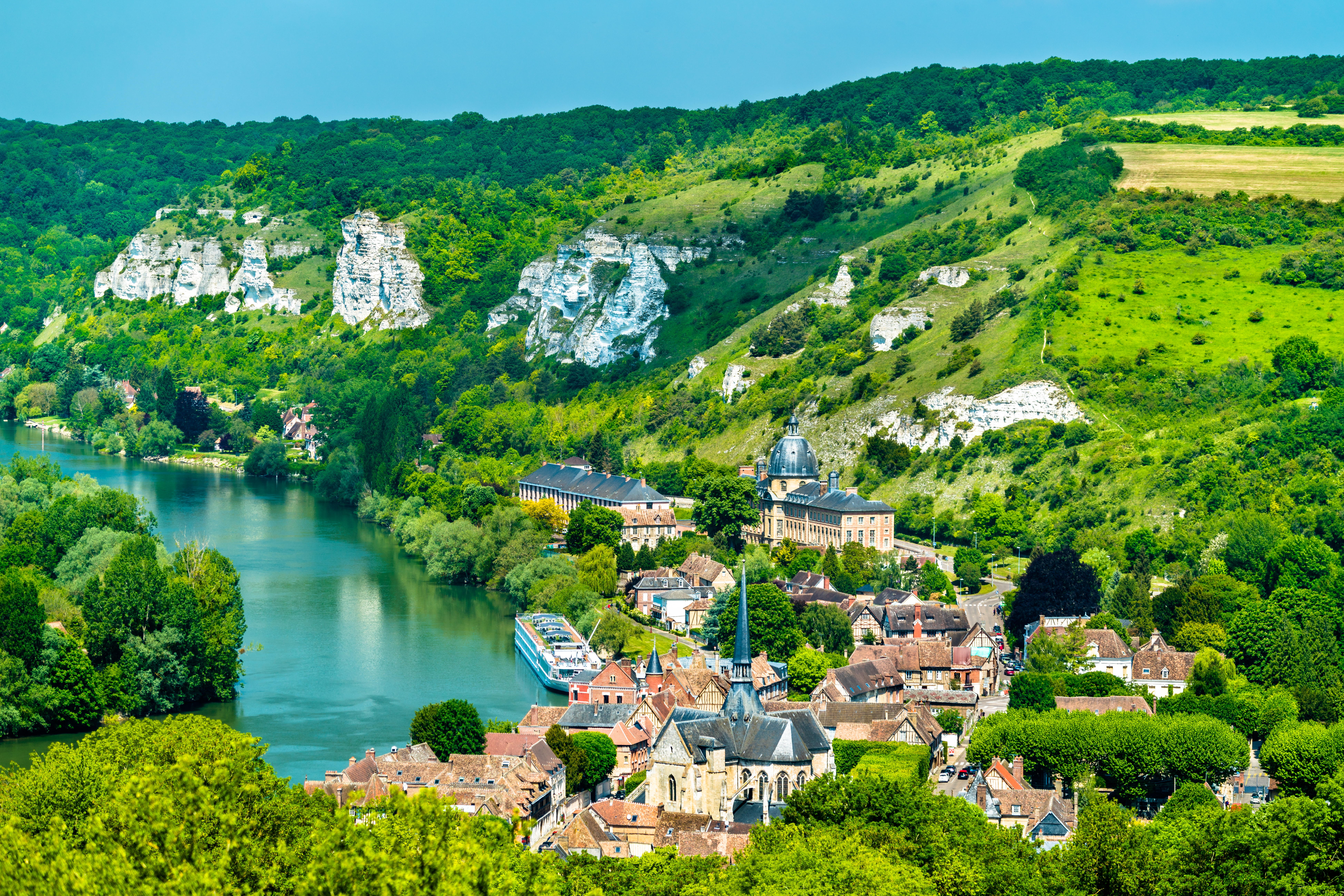Betagende panorama over Les Andelys-kommunen med dens historiske bygninger langs Seine-floden, indrammet af det smukke normanniske landskab og resterne af den middelalderlige borg Château Gaillard