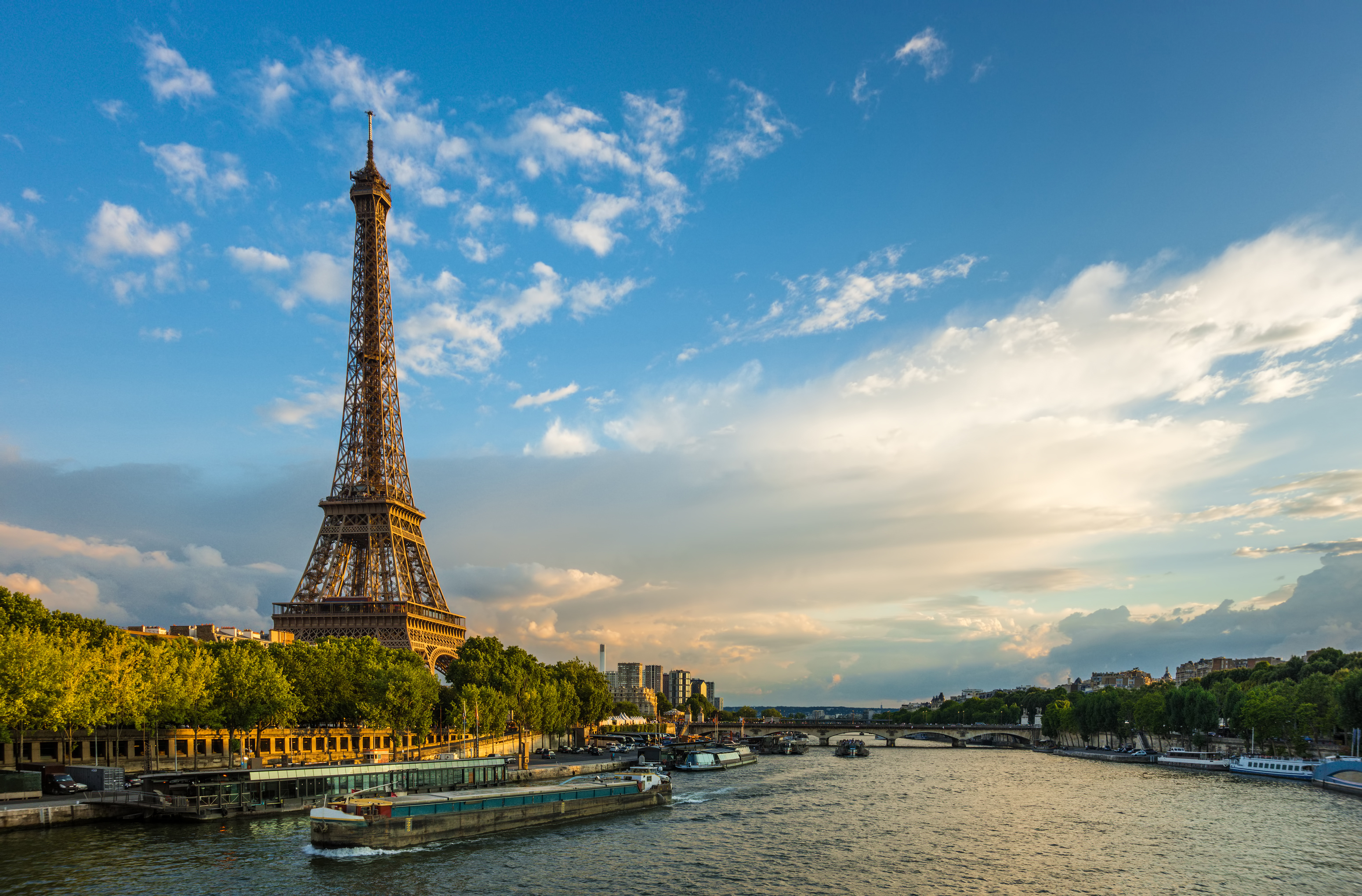 Betagende aftenstemning ved Eiffeltårnet og Seine-floden med turistbåde under en farverig himmel i Paris