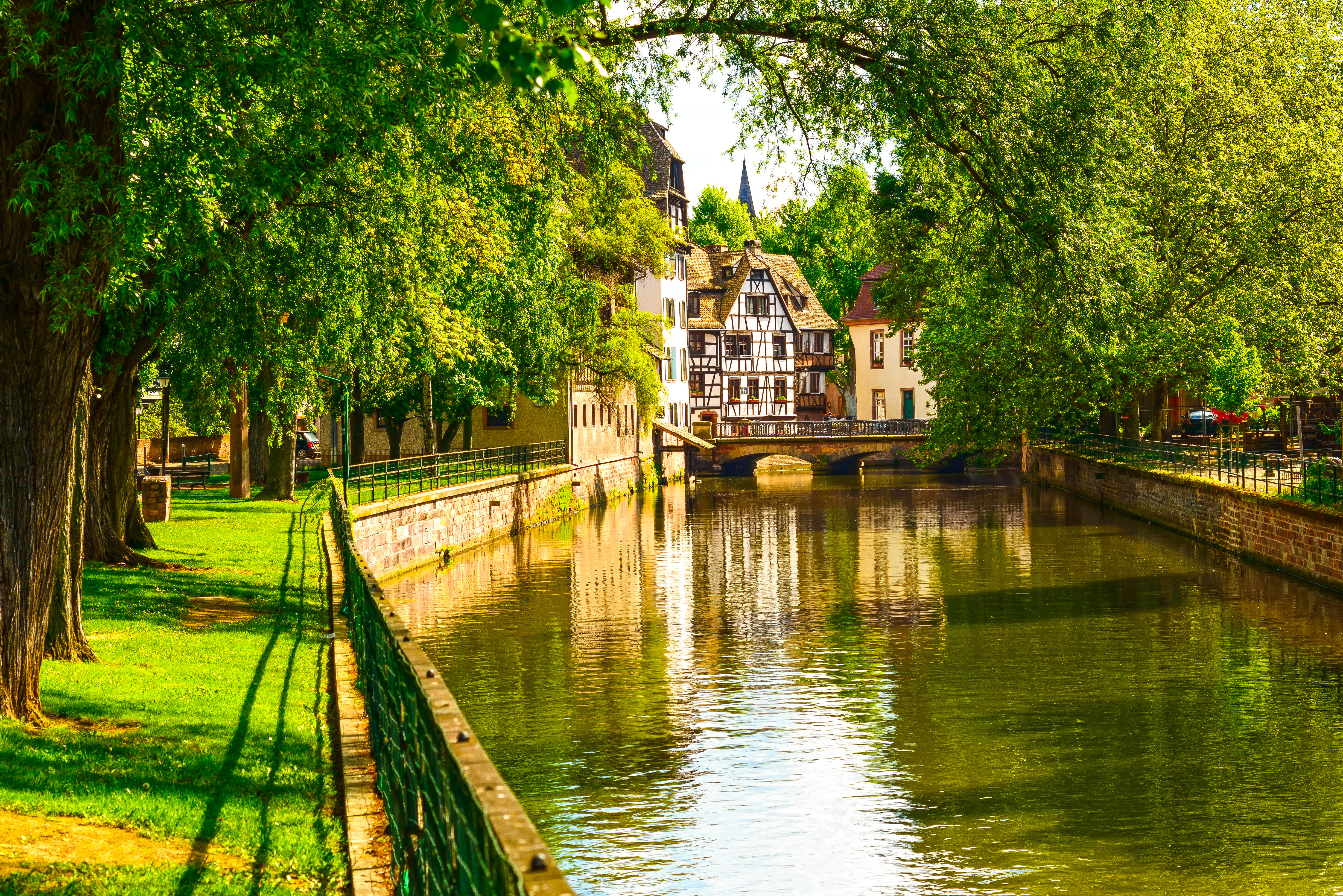 Charmerende udsigt over vandkanalen i Petite France-området i Strasbourg med karakteristiske bindingsværkshuse og frodig vegetation, Alsace, Frankrig
