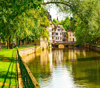 Charmerende udsigt over vandkanalen i Petite France-området i Strasbourg med karakteristiske bindingsværkshuse og frodig vegetation, Alsace, Frankrig