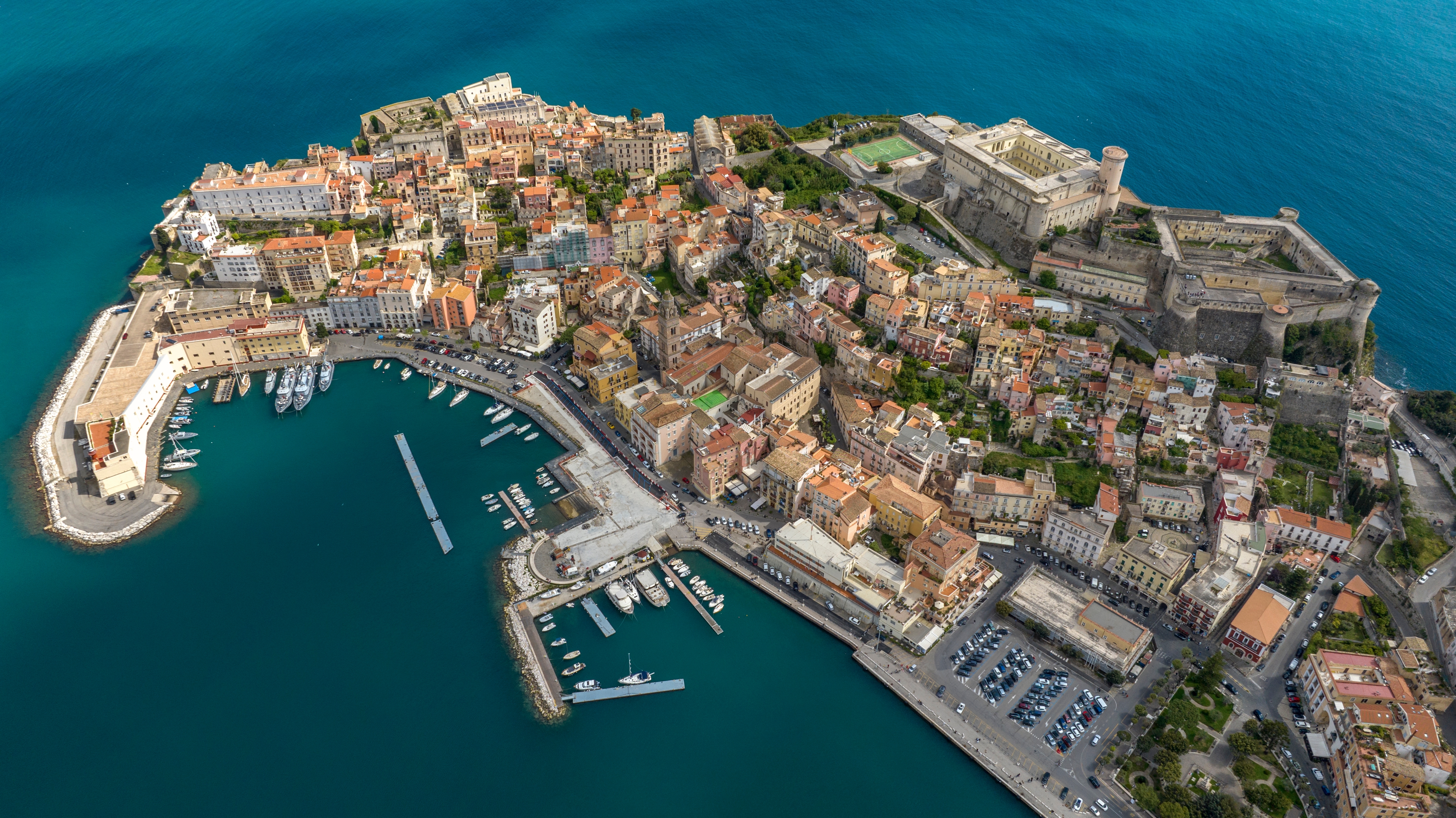 Storslået fugleperspektiv over den historiske italienske kystby Gaeta ved Middelhavet med gammel fæstning, havn med lystbåde og farverig bebyggelse i Lazio