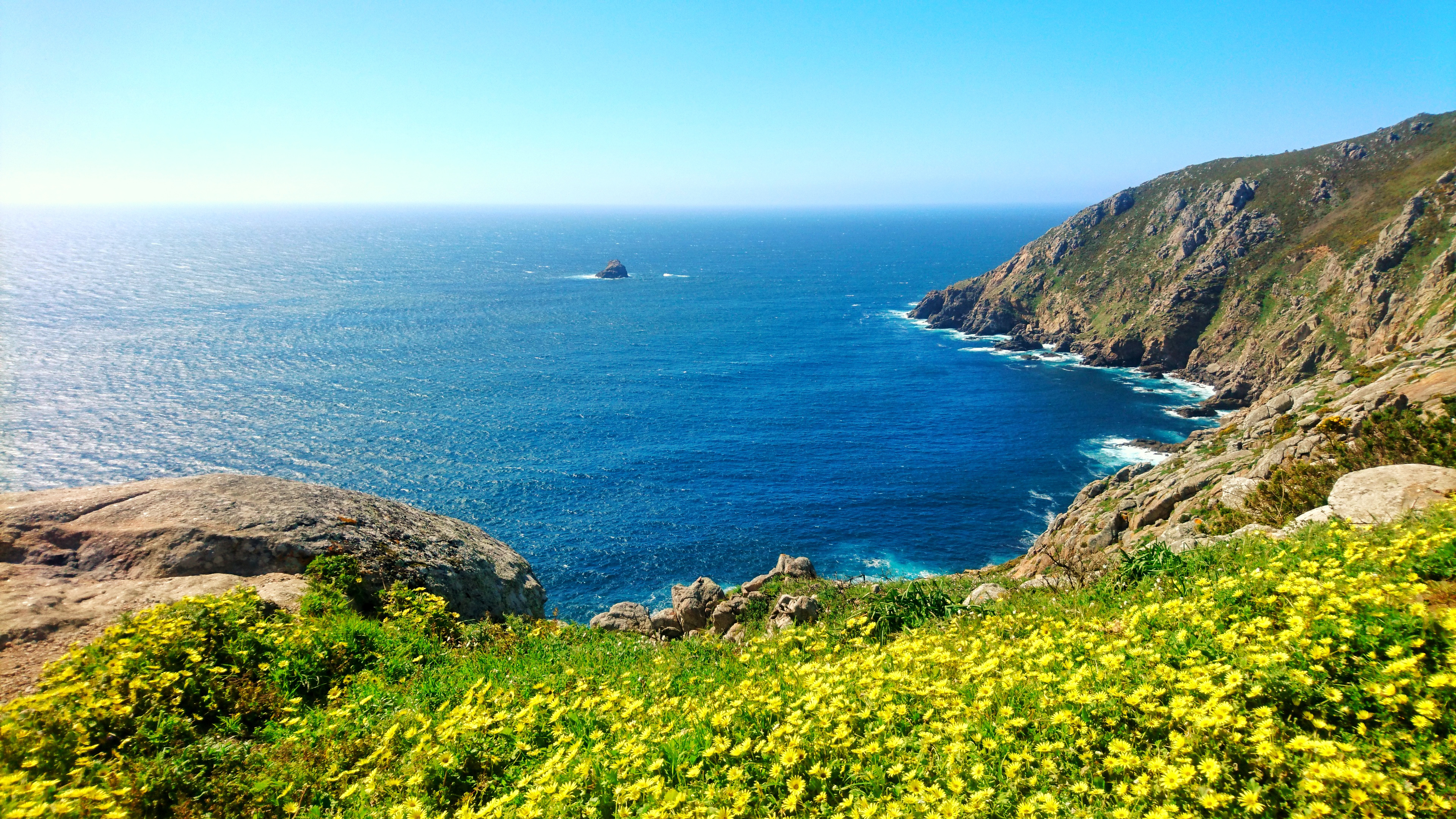Smuk atlantkyst ved Cape Finisterre i Galicien med blomstrende flora og turkisblåt hav