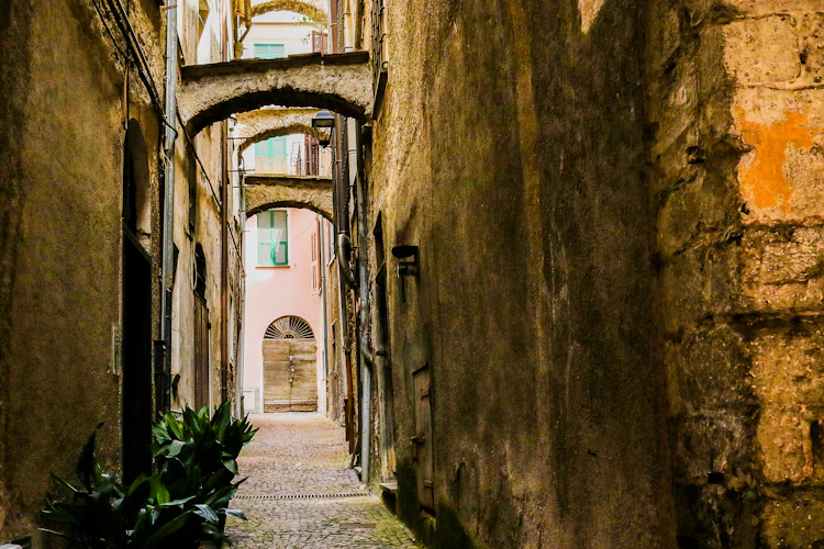 Romantisk smal gyde med historiske stenarkader i den lille by Pieve di Teco i det nordlige Italien