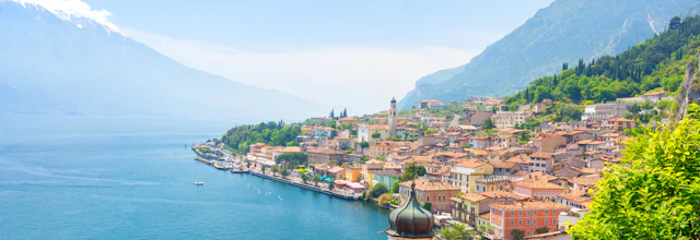 Idyllisk udsigt over Limone sul Garda ved Gardasøen med charmerende italiensk arkitektur og sneklædte alper i horisonten