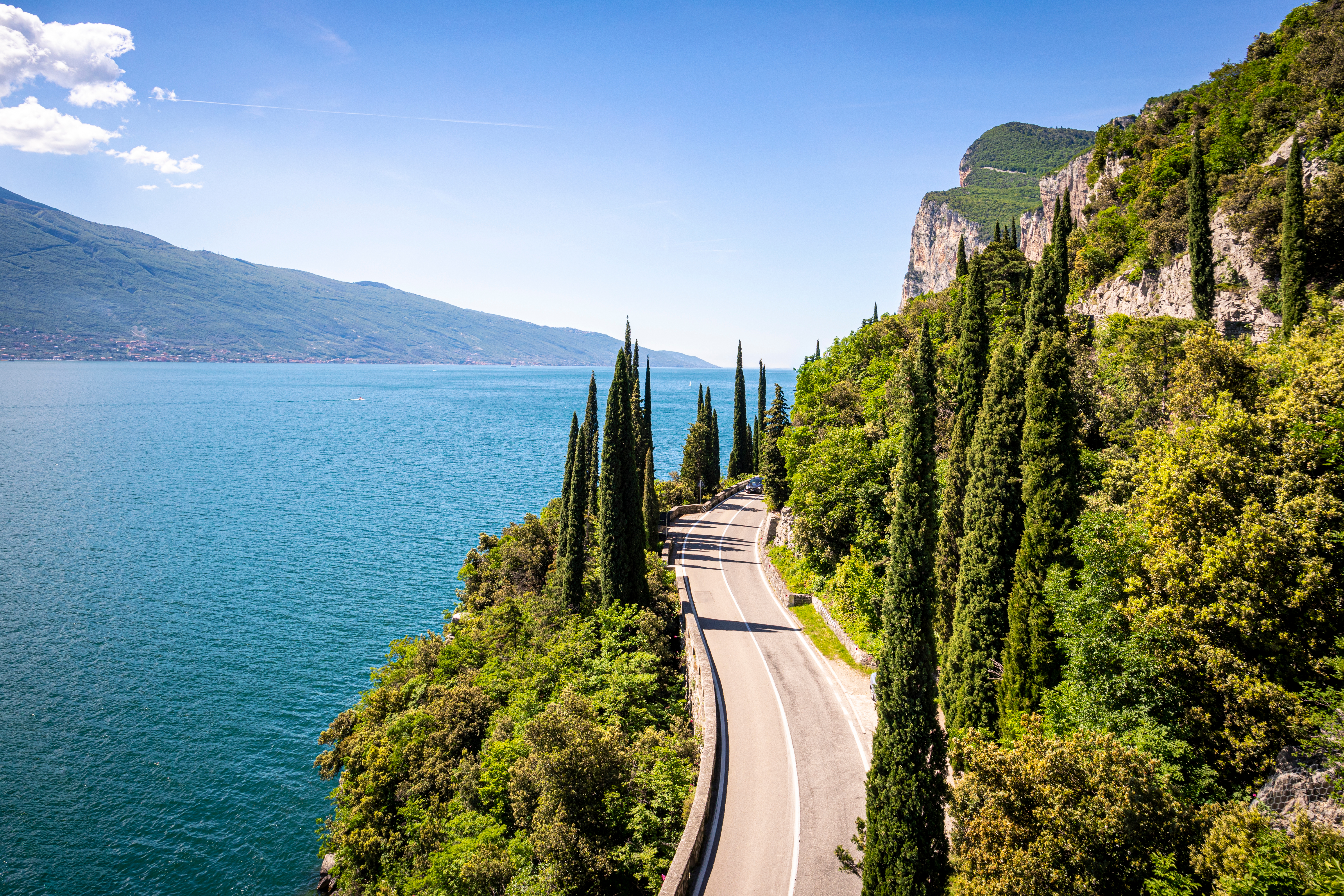 Snoet scenic road langs Gardasøens klipper med smukt turkisblåt vand og grønne cypresser i Italien
