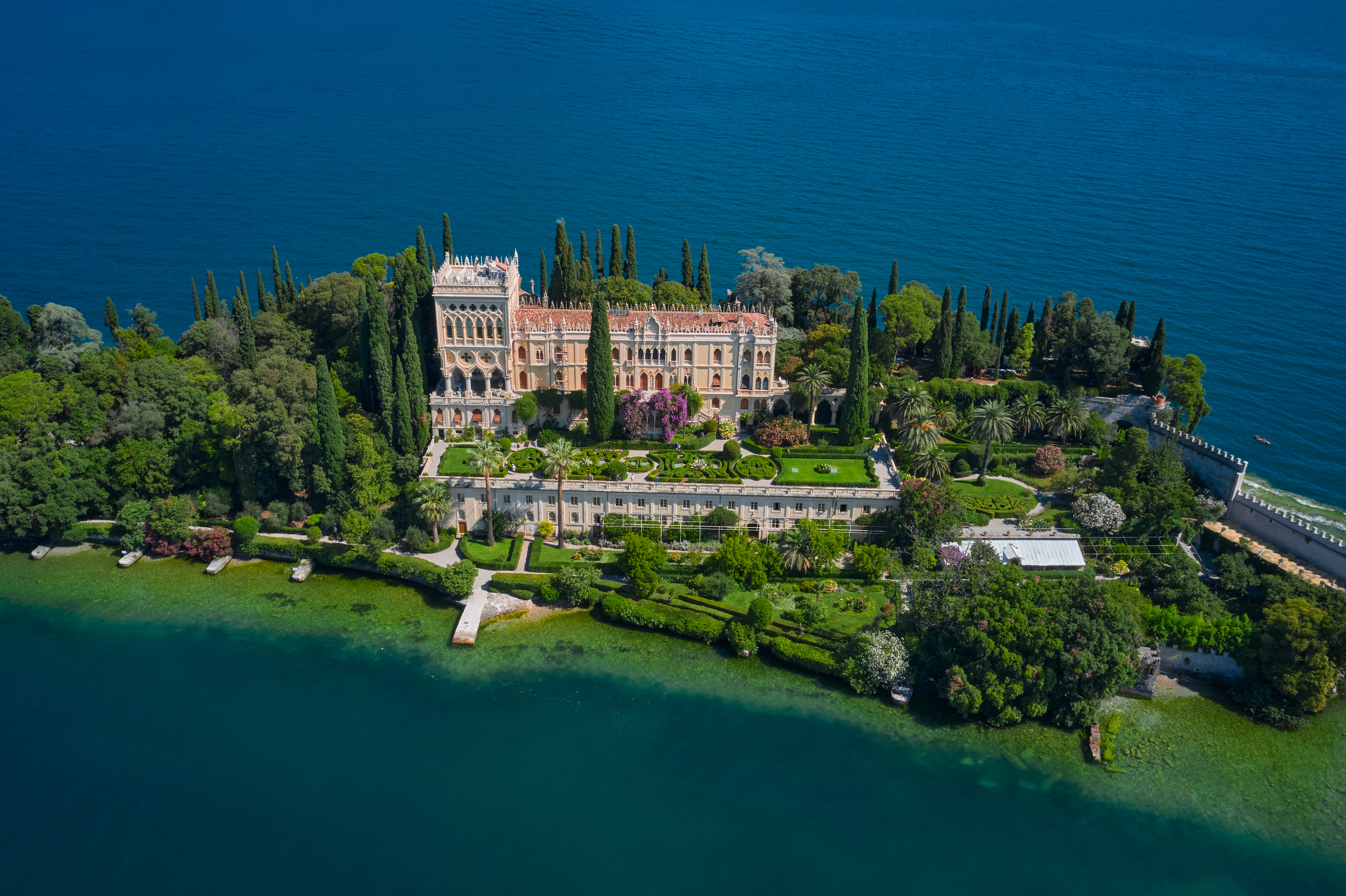 Drone-foto af Isola del Garda, Gardasøens største ø, med historisk italiensk villa, cypressalléer og smukke parkanlæg omgivet af blåt vand