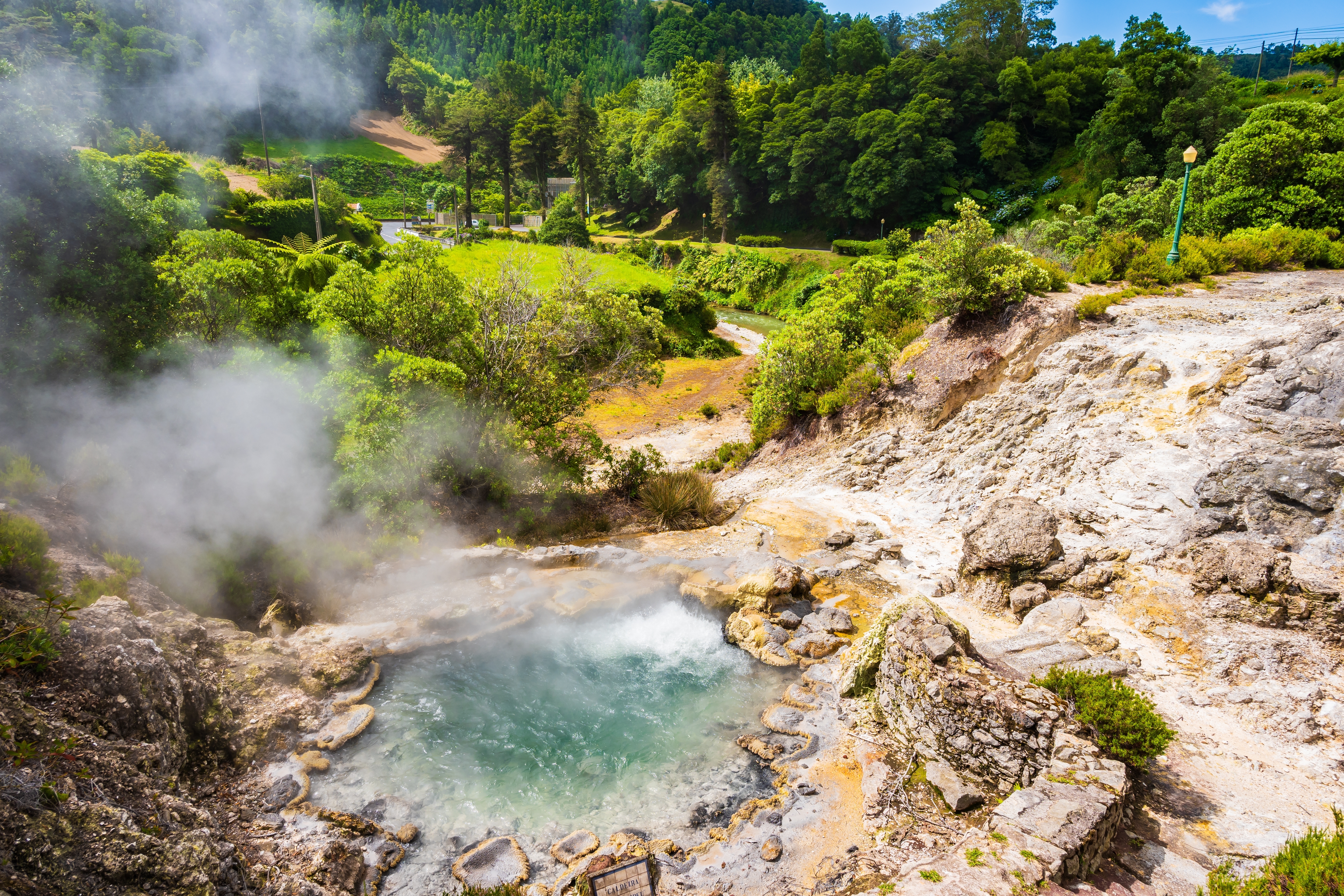 Geotermiske kilder på vulkansk ø i Portugal med krystalklart vand og naturlig damp omgivet af grøn vegetation