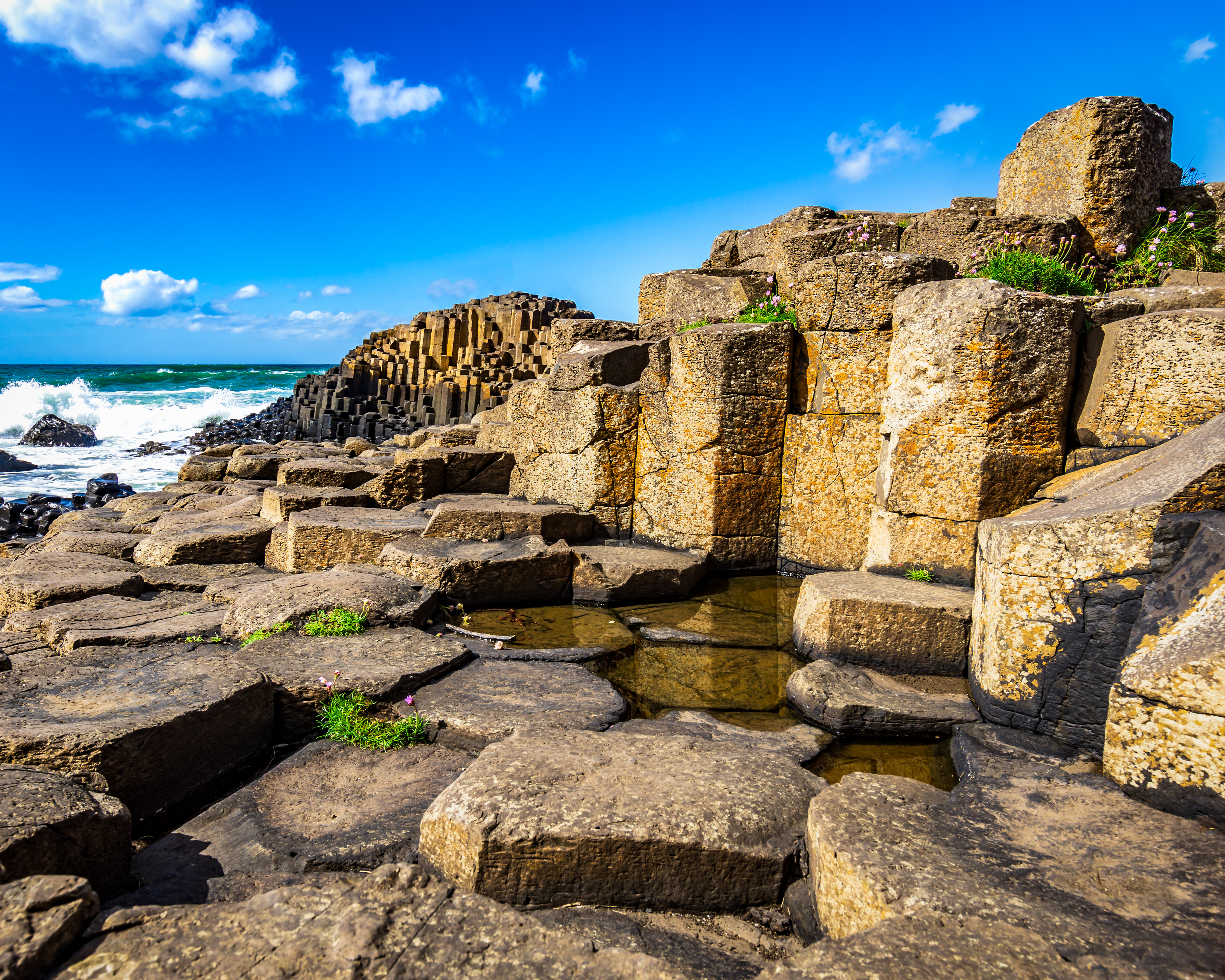 Dramatisk kystlandskab ved Giant's Causeway med antikke ruiner og naturlige basaltformationer