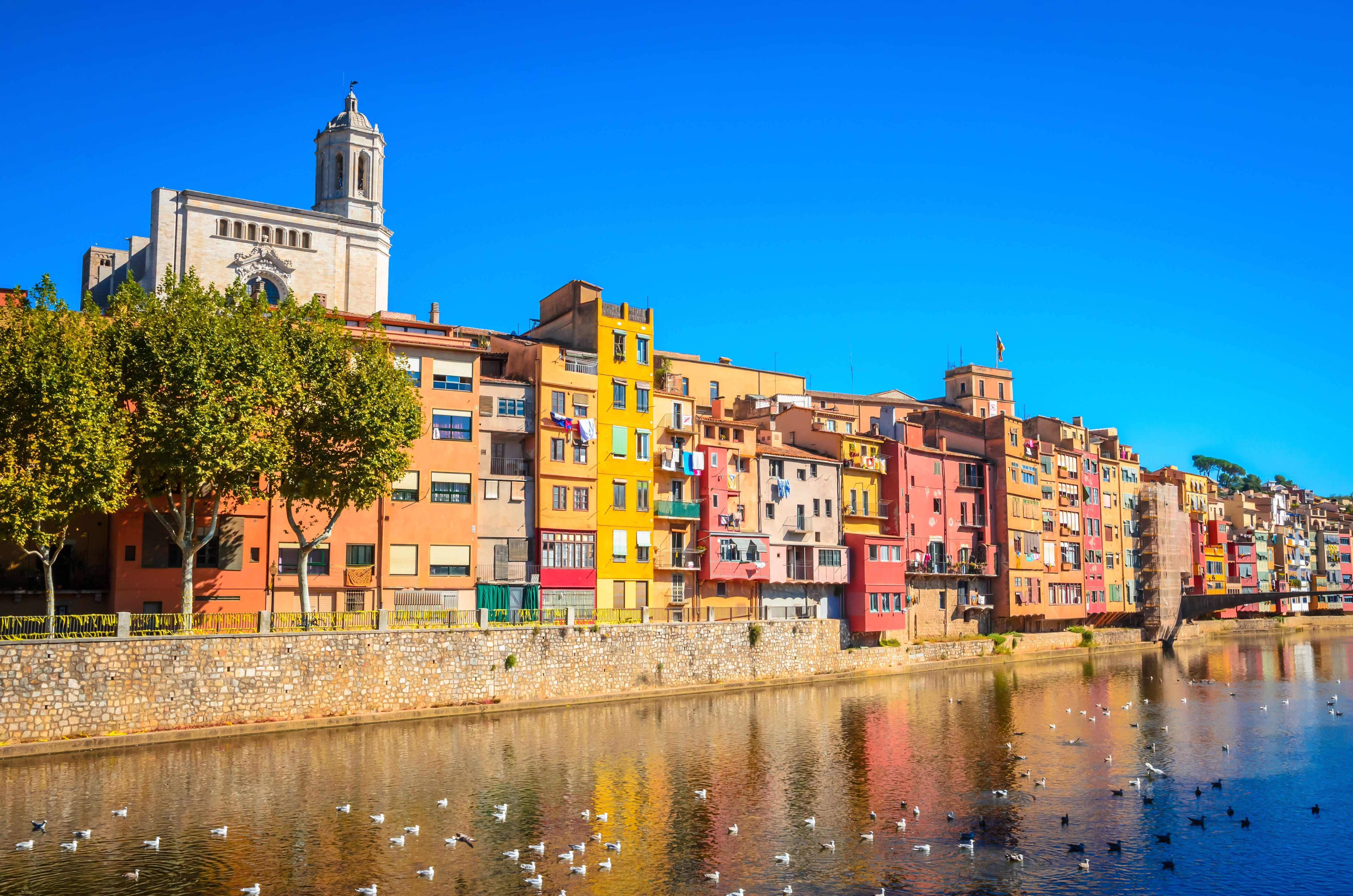 Idyllisk udsigt over Gironas farvestrålende bolighuse ved Onyar-floden med den berømte katedral i baggrunden i Catalonien