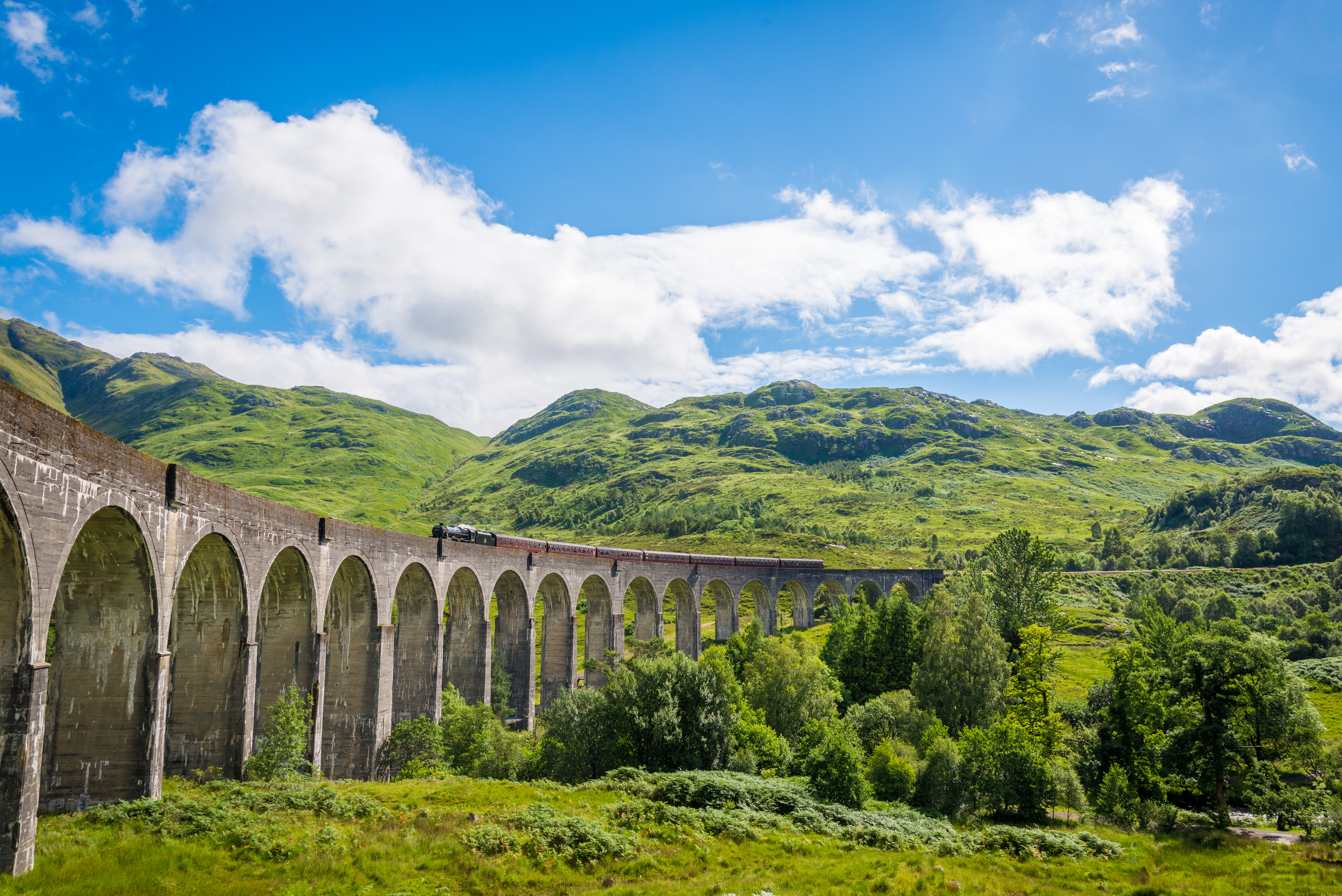 Majestætisk Glenfinnan togbro gennem de skotske højlandes grønne natur
